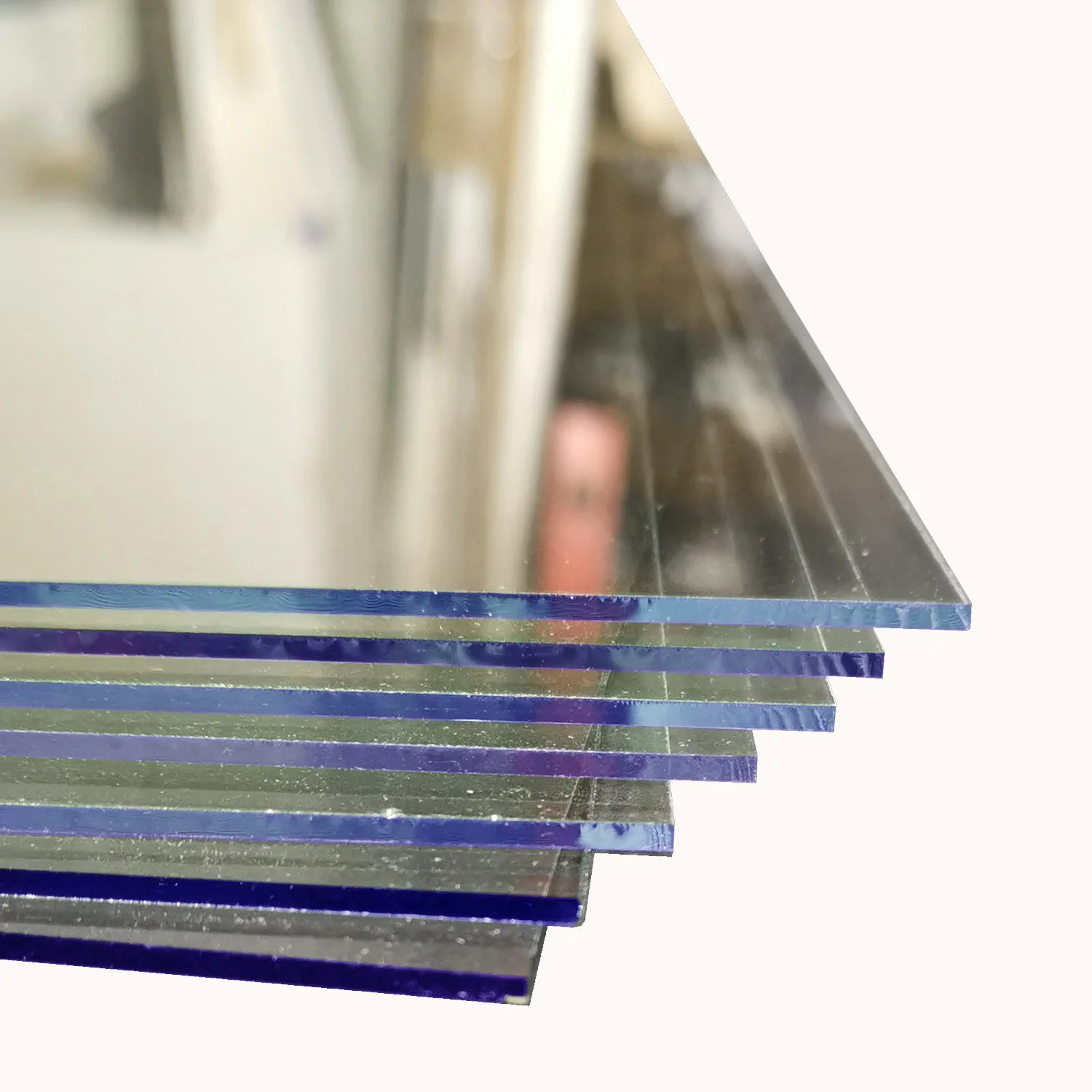 Stacked glass sheets with reflections and edges visible, placed on a reflective surface.