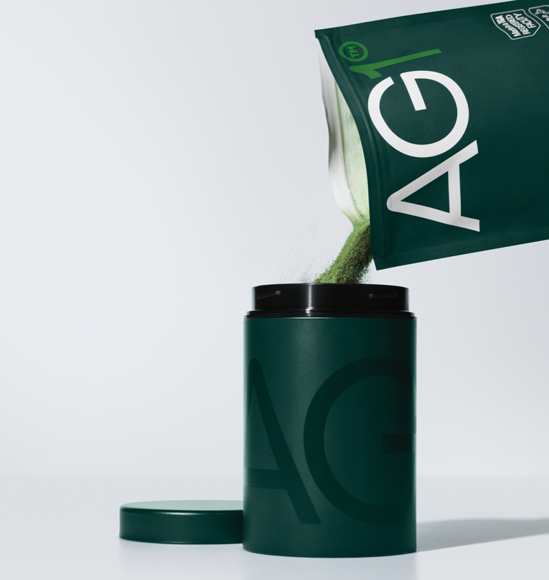 Athletic Greens. Green powder being poured out of a pouch into a thermos.