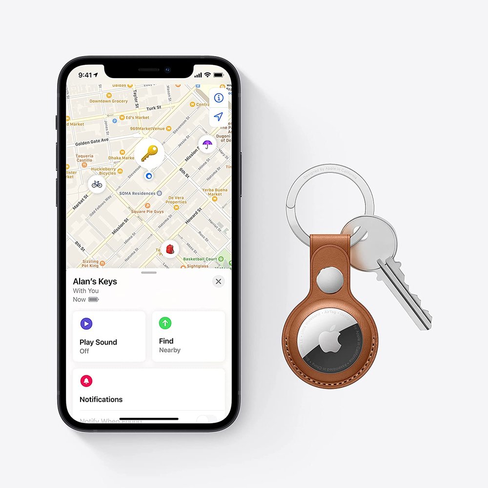 Apple AirTag on a keyring next to a phone