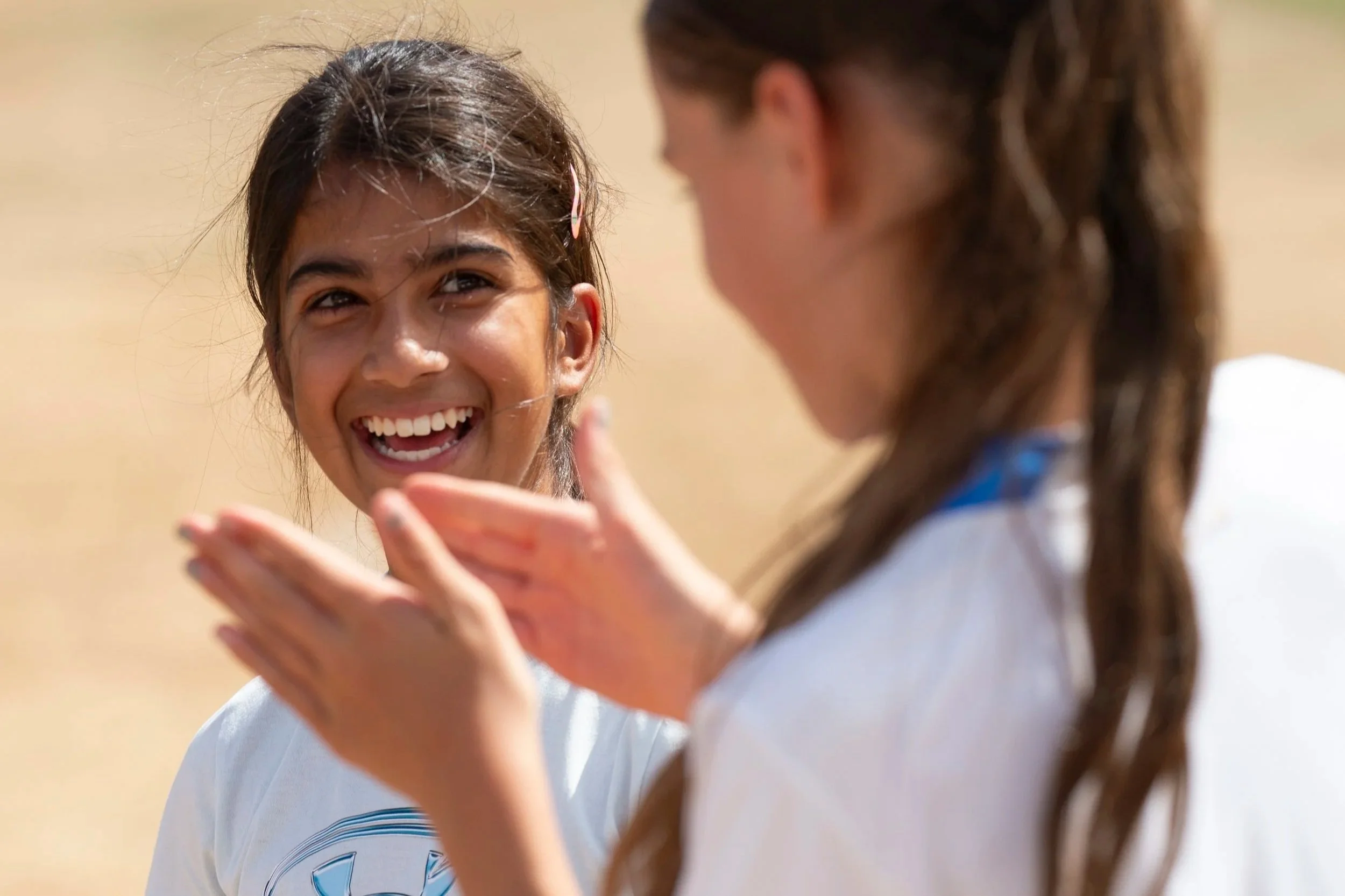 Girl smiles while looking at another girl who is blurry in image