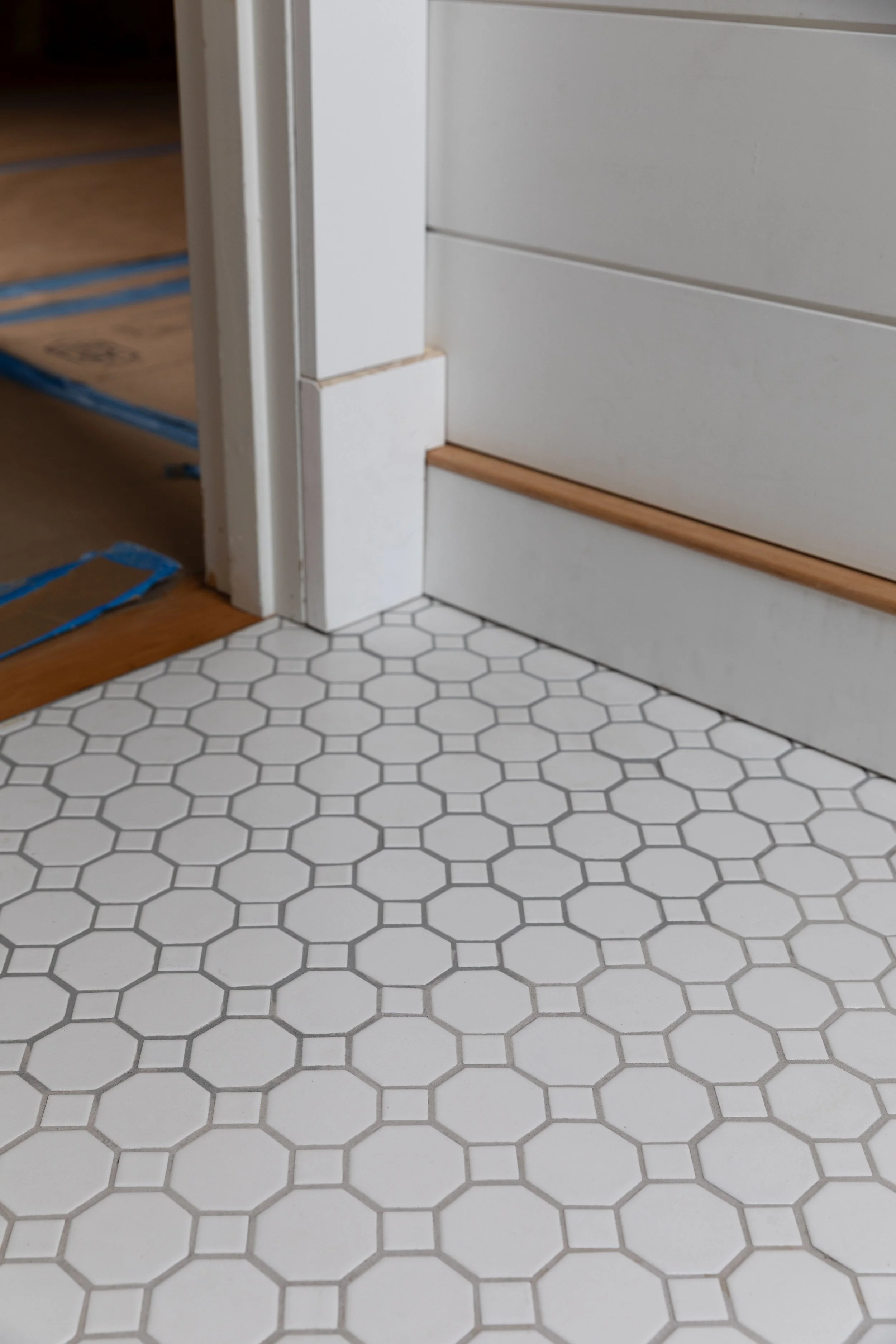 Bathroom tile floor showing lighter epoxy grout in foreground and darker grout in background