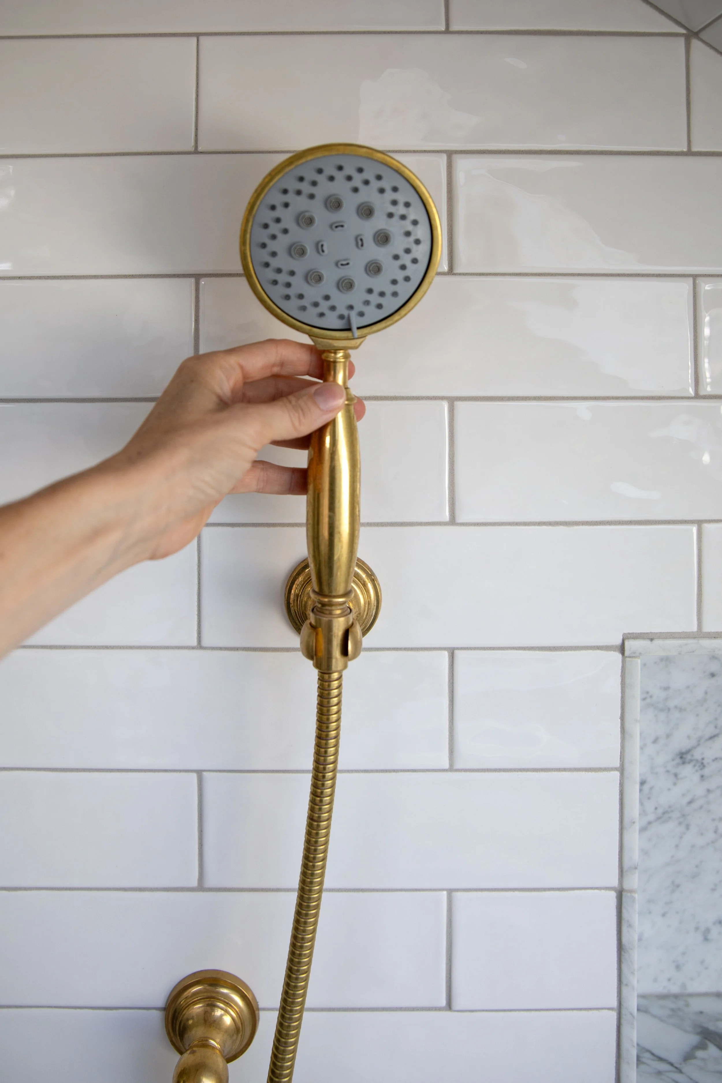 Hand shower with cord mounted on white subway tile