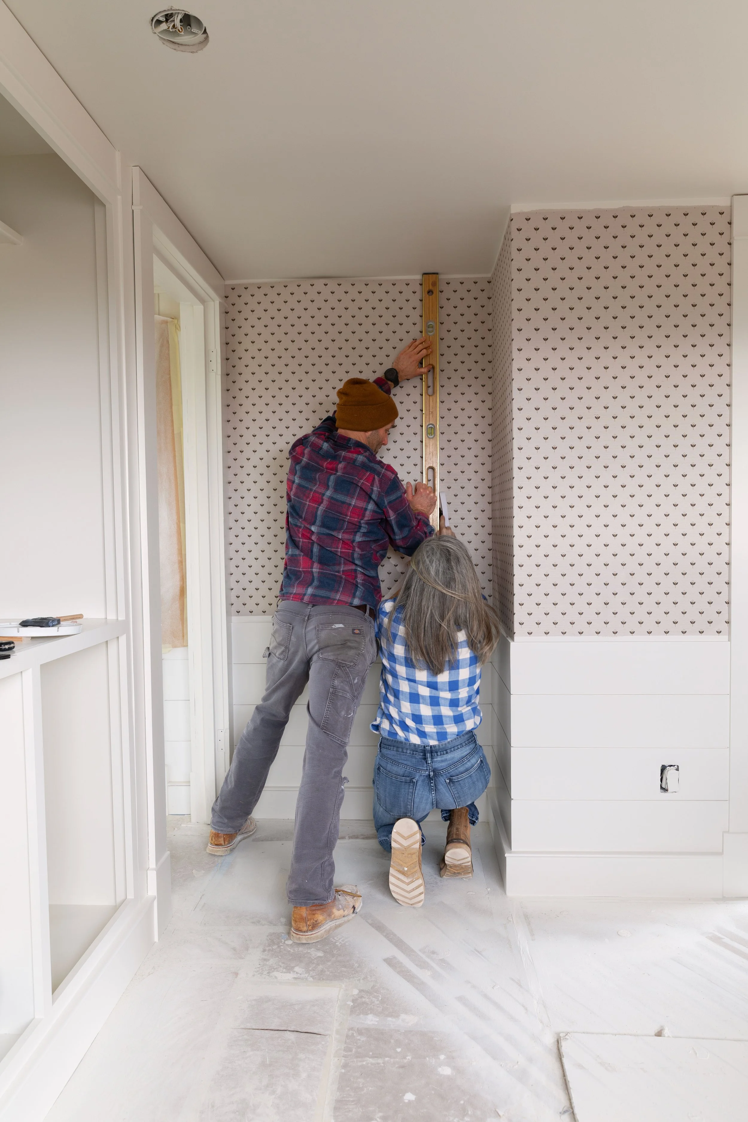 Installing grasscloth wallpaper together in a bedroom renovation at the Hill House