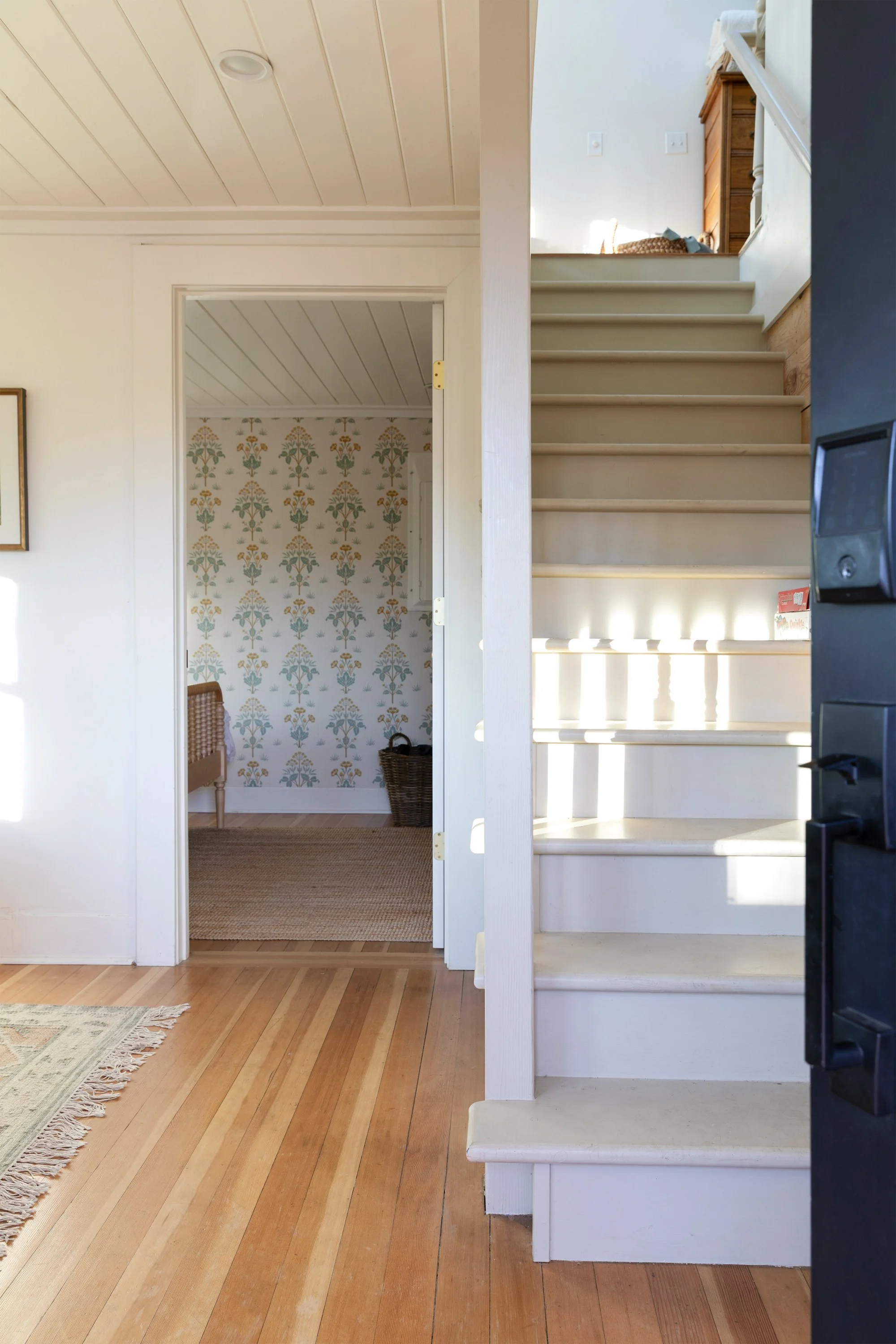 View from front door into sitting and dining room with staircase and primary bedroom visible beyond