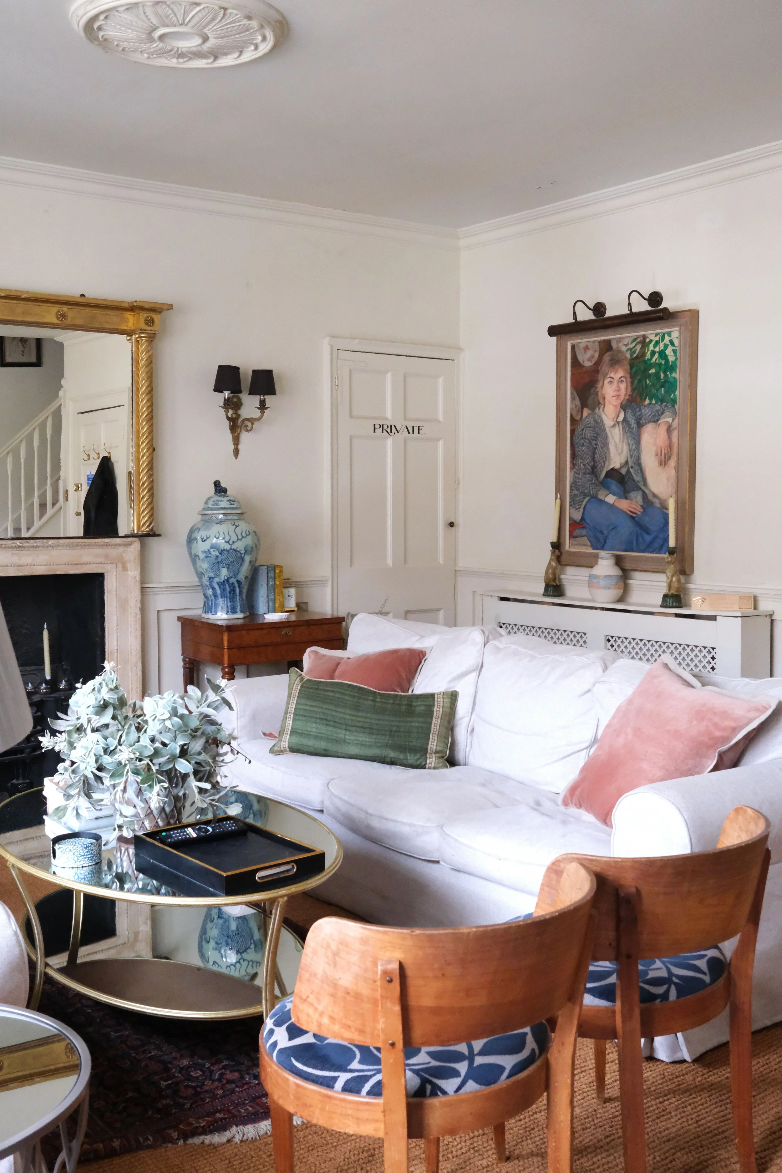 Collection of vintage paintings and gilt frames on the white walls of an English living room