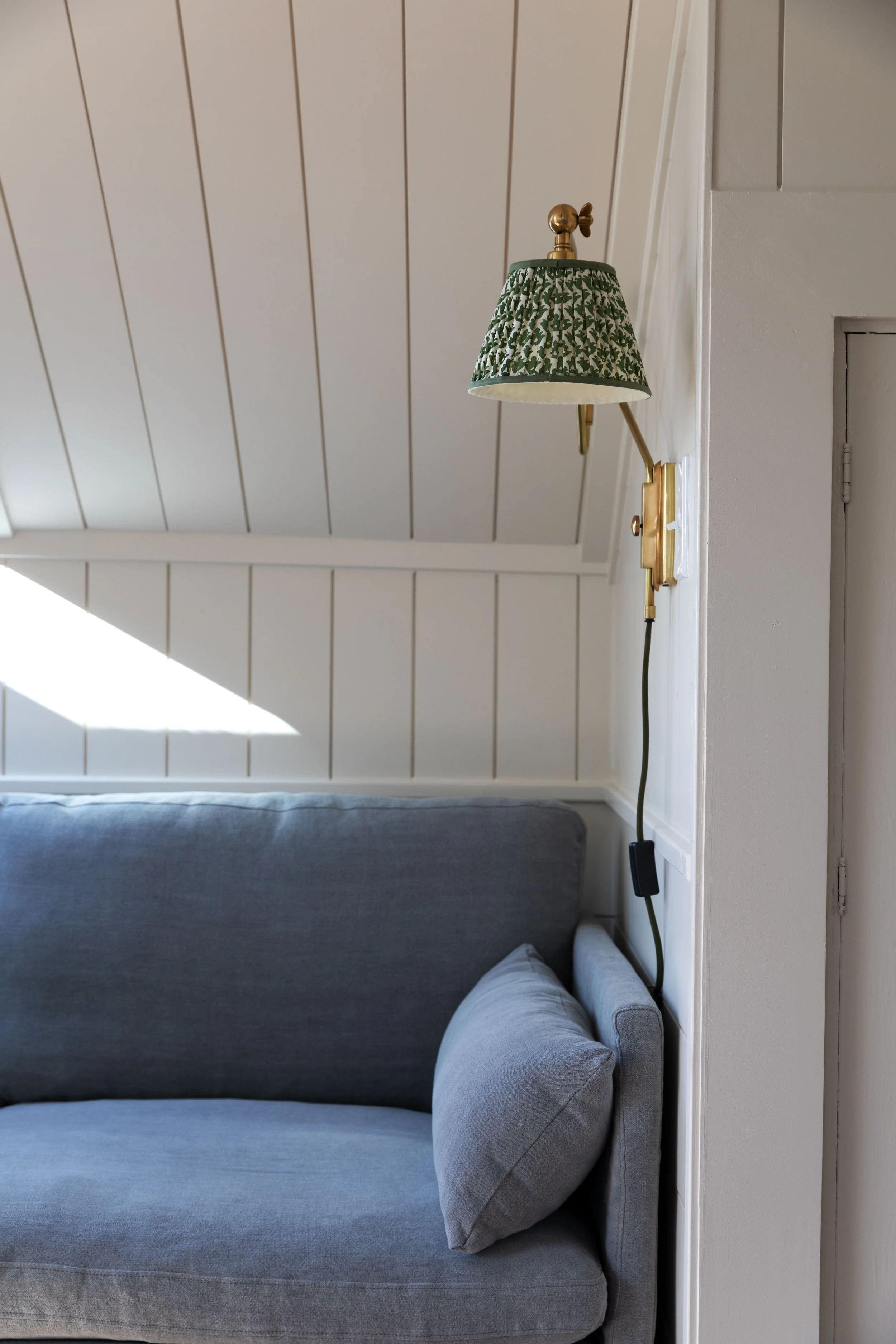 Small living room with pull-out reading sconce above a linen sectional sofa