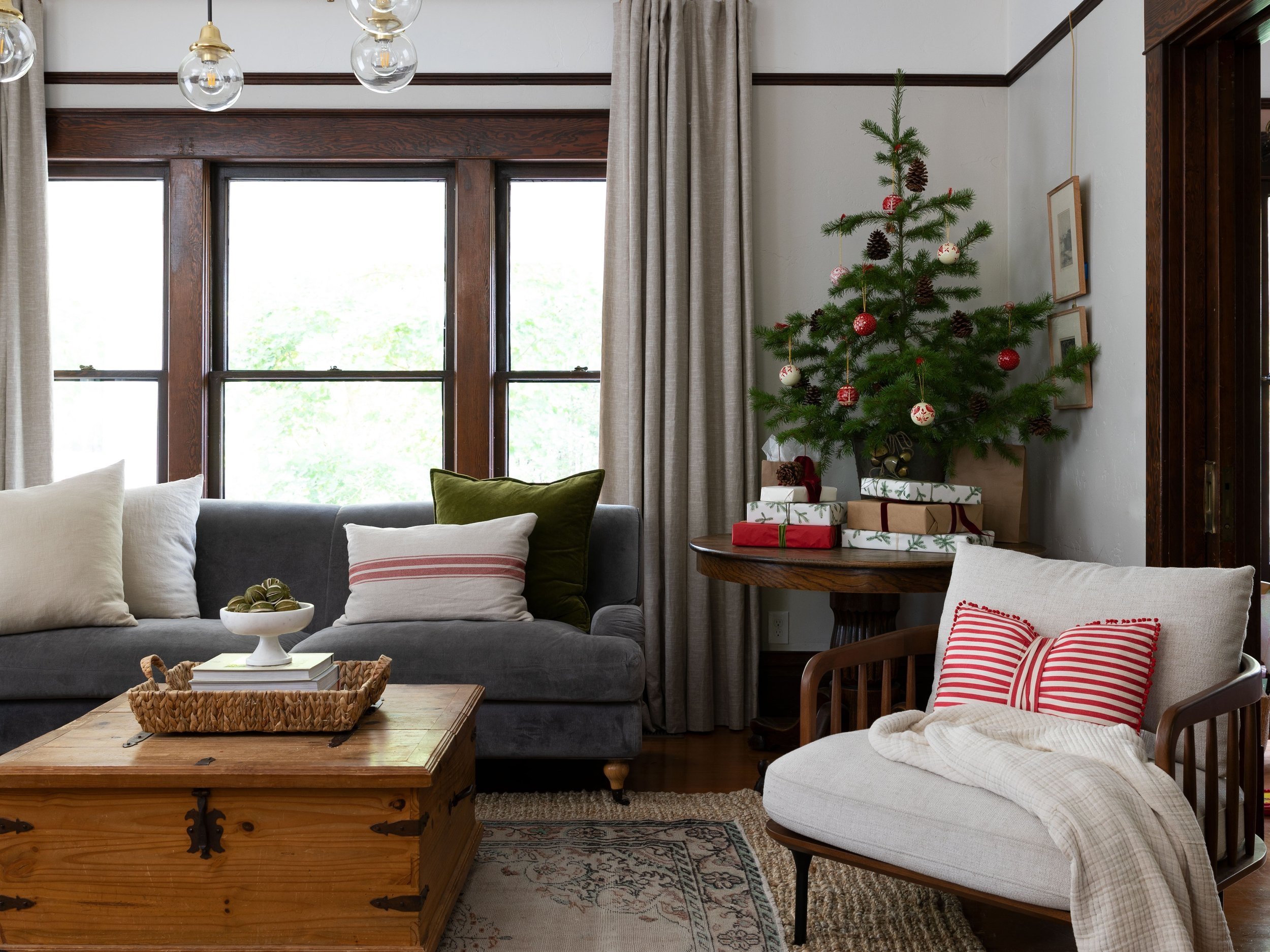 Historic farmhouse living room with a classic Christmas tree and red pillow — cozy old-house holiday decor.