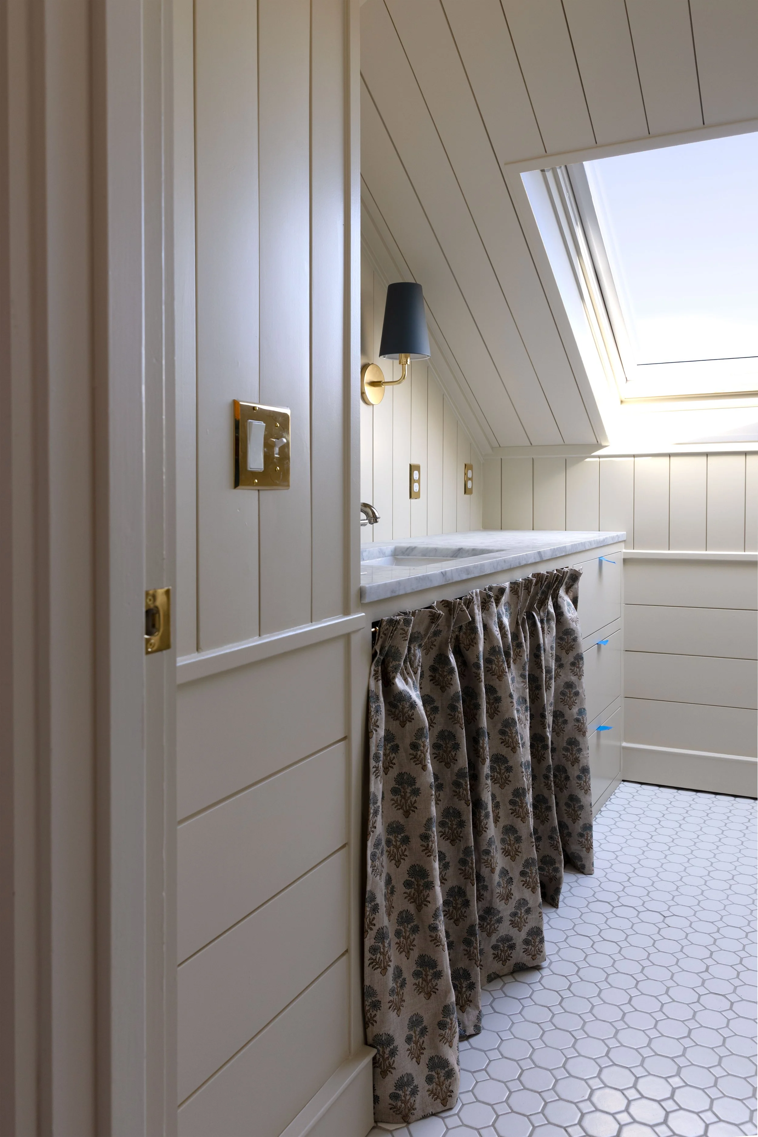Cabinet skirt used as a solution for an awkward bathroom vanity in a sloped old house space