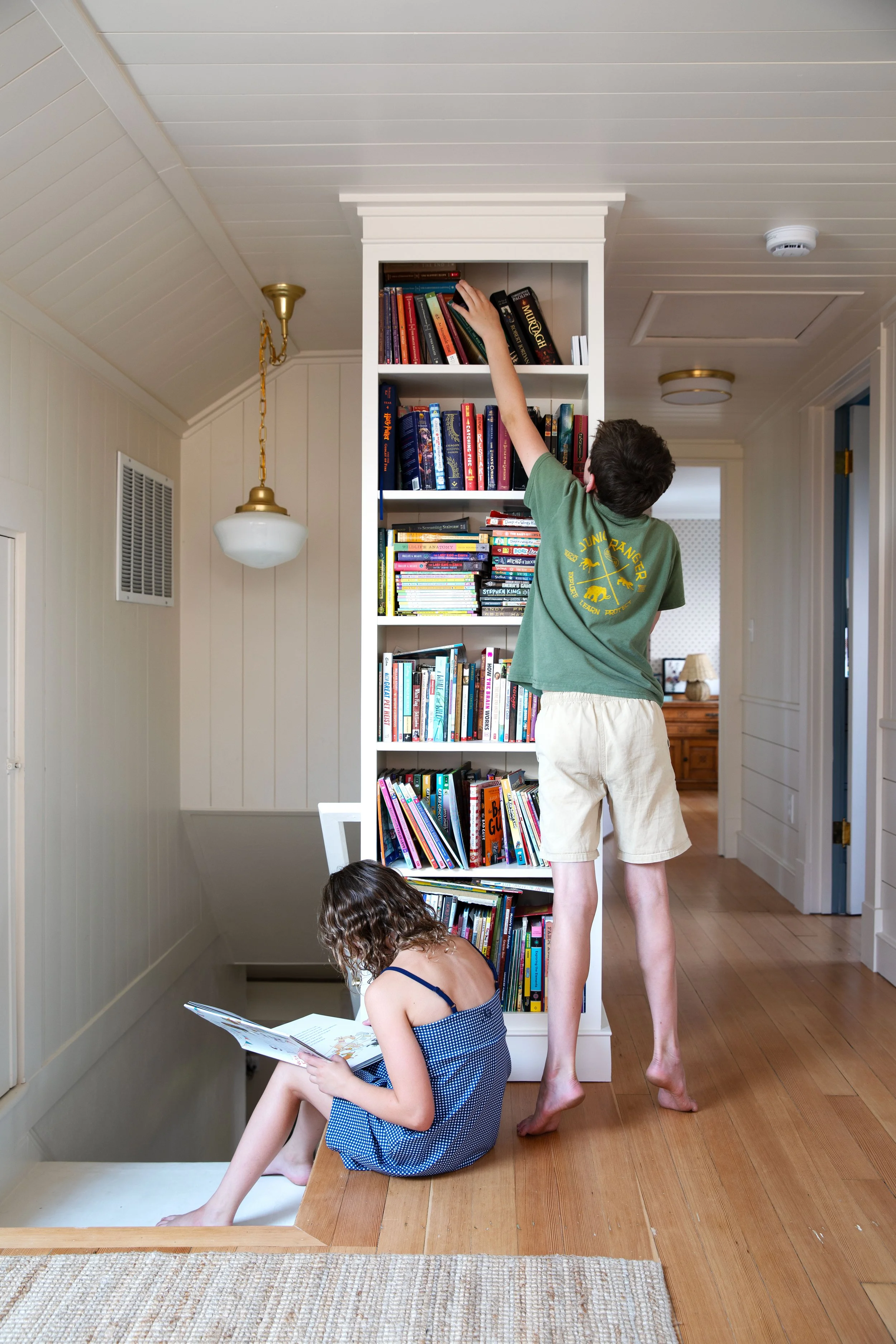 Kids choosing books from the built-in bookcase at the top of the Hill House stairs