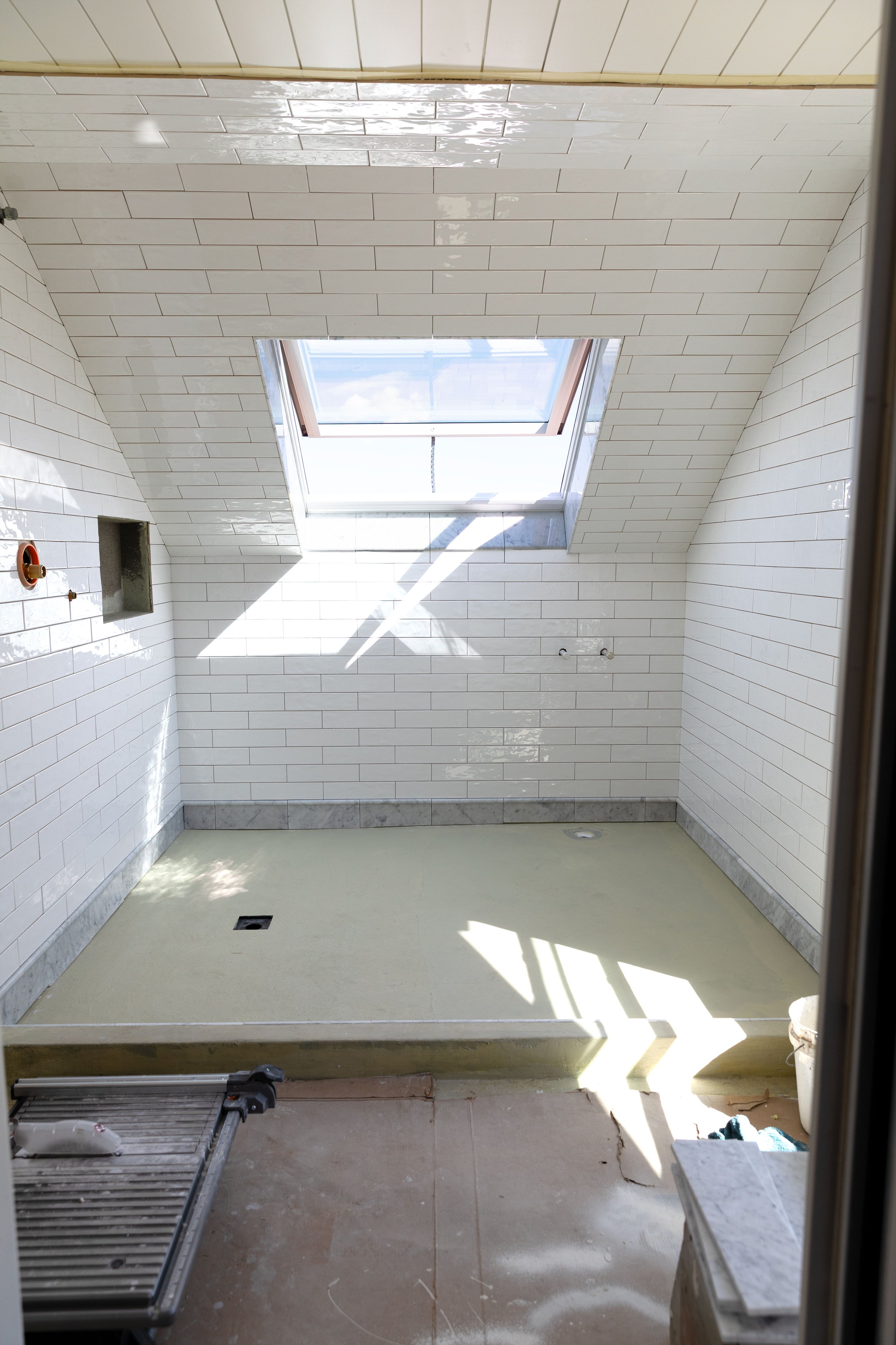 Wet room progress with white subway tile and marble base