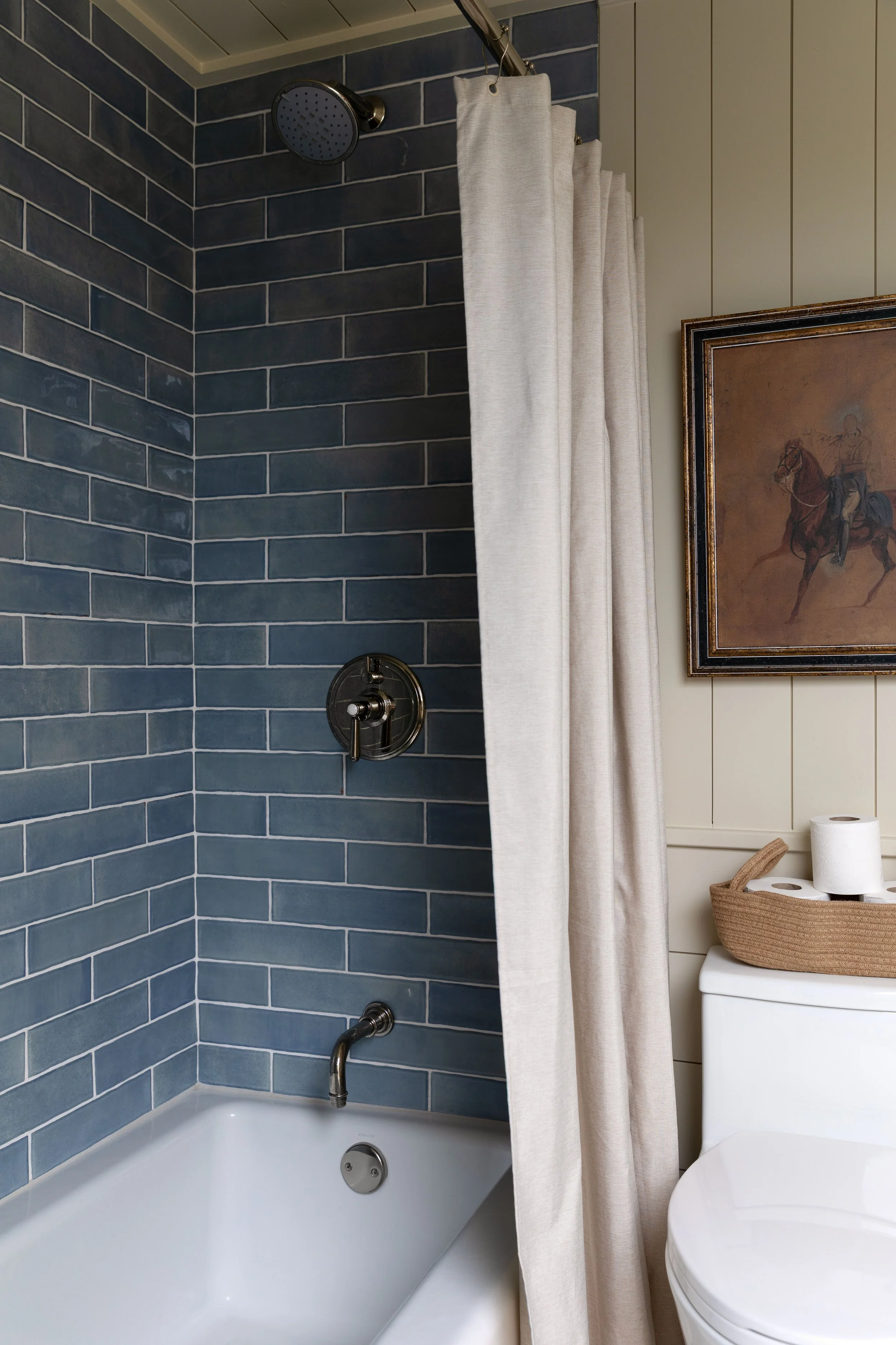 Blue subway tile in shower with iron-colored epoxy grout in the Hill House hall bathroom