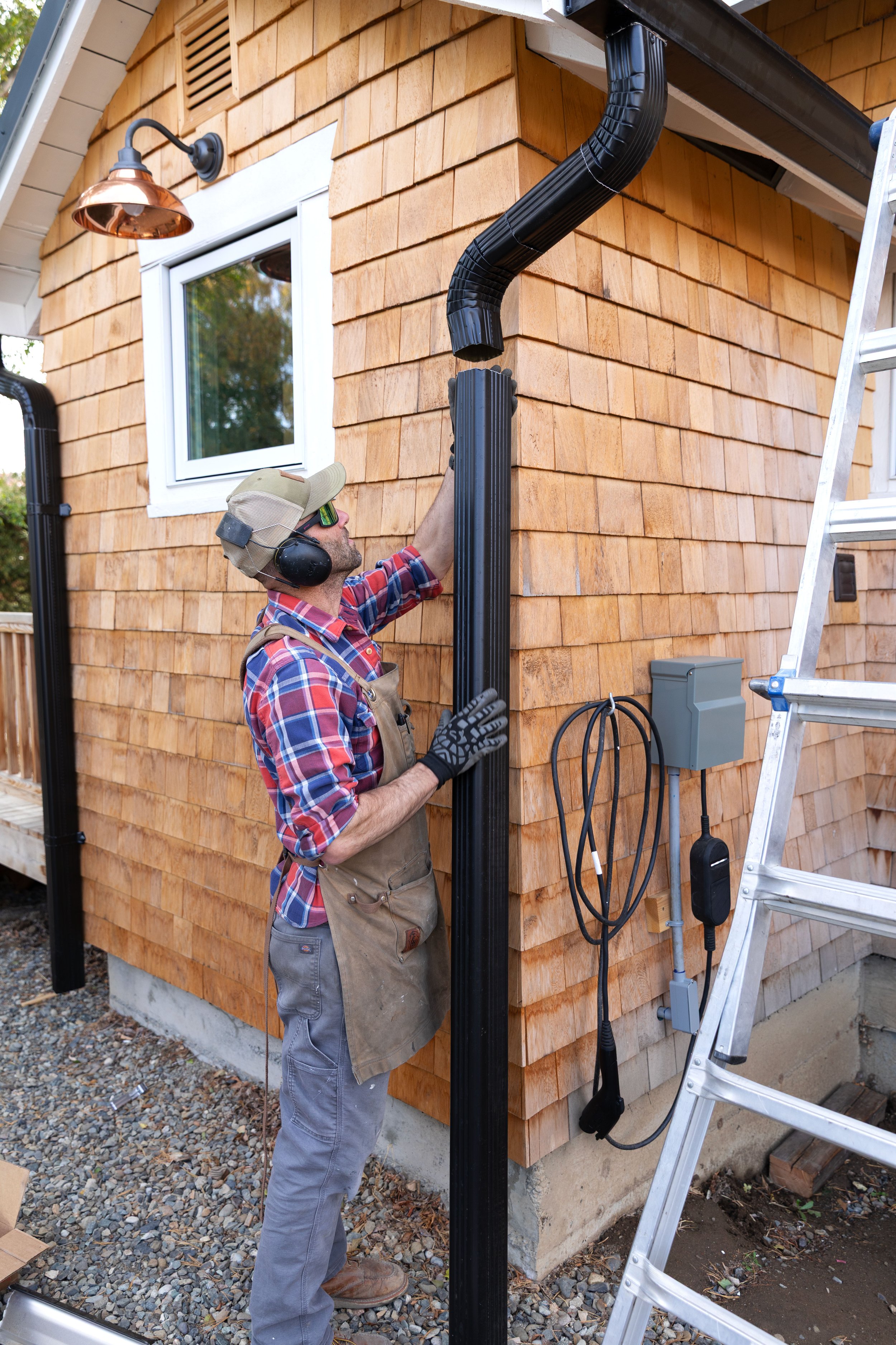Adding a black metal downspout to DIY gutters at the Poplar Cottage