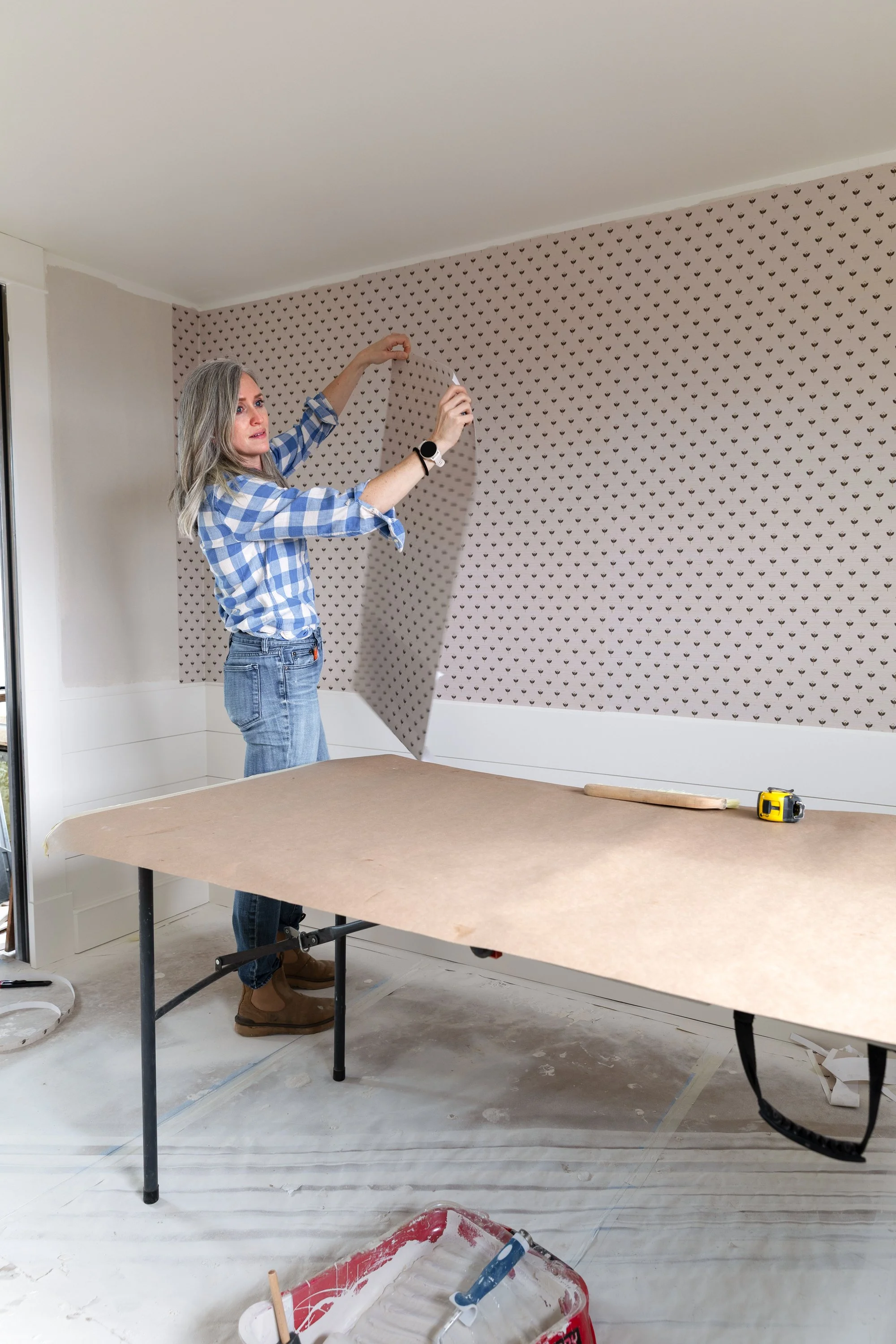 Holding grasscloth wallpaper after pasting and booking before installing on the wall