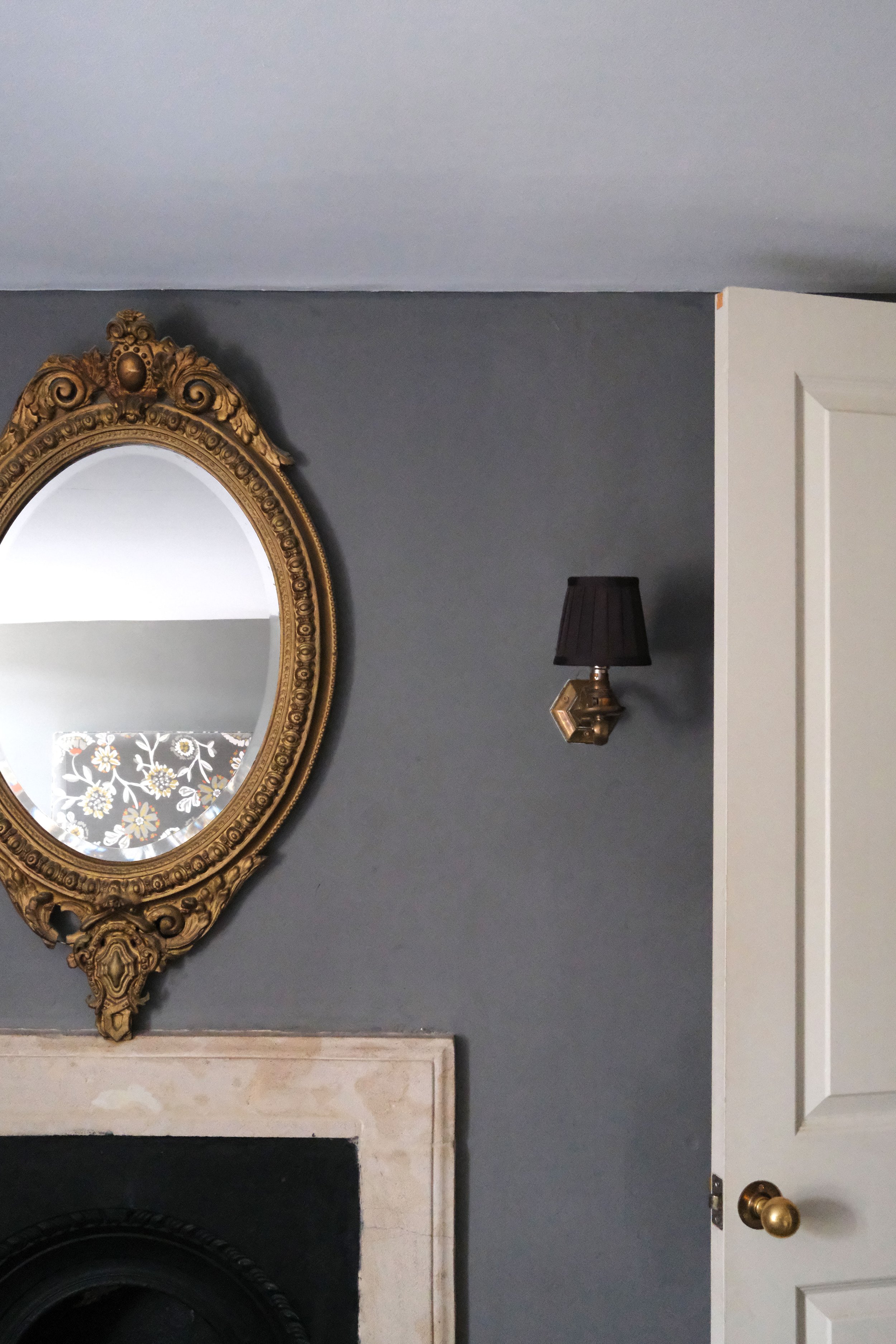 Soft gray bedroom with antique portraits, brass details, and dark wood furniture