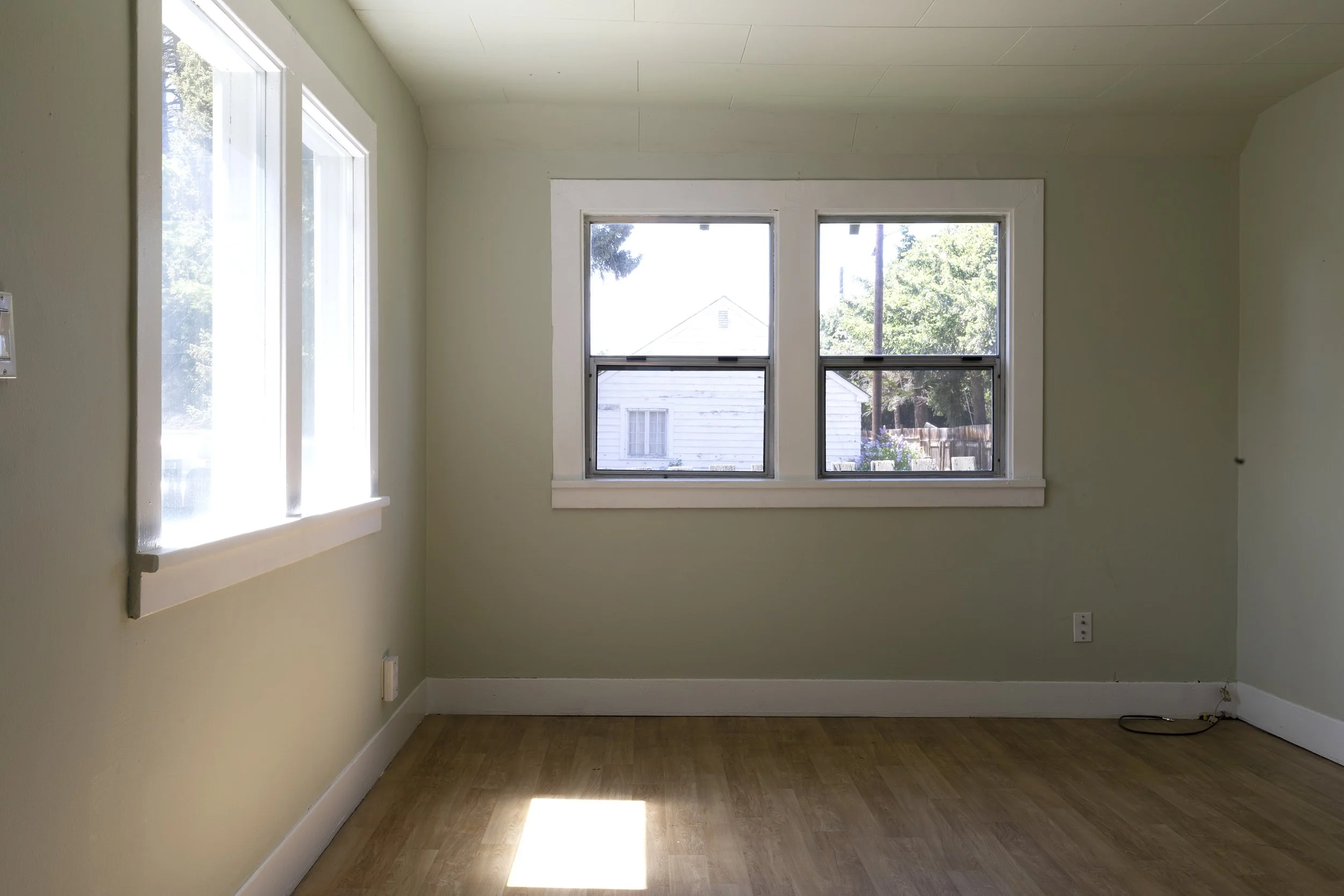 Before photo of the Poplar Cottage dining room with acoustic ceiling tiles, pergo floors, and original metal windows