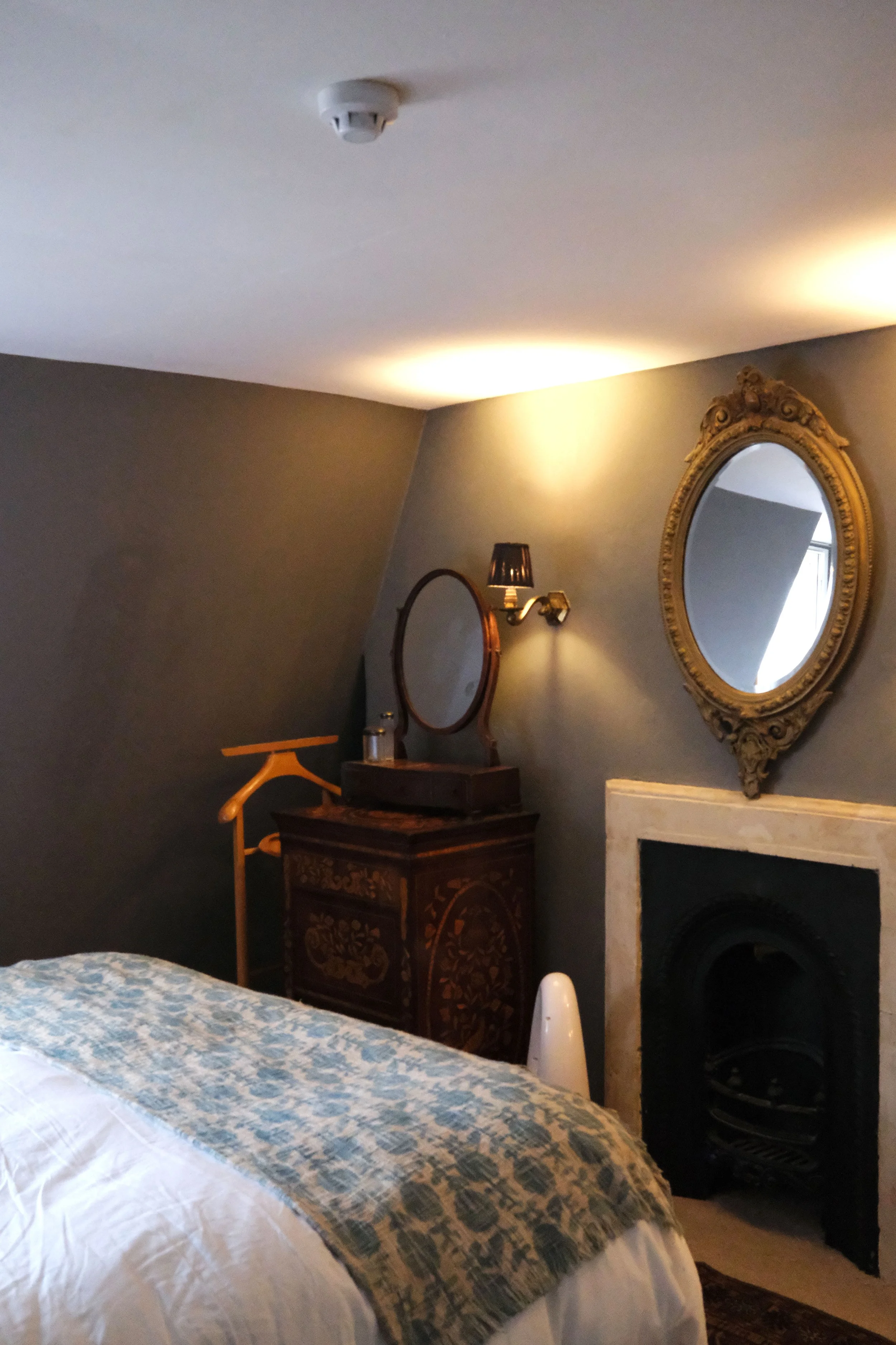 Soft gray bedroom with antique portraits, brass details, and dark wood furniture