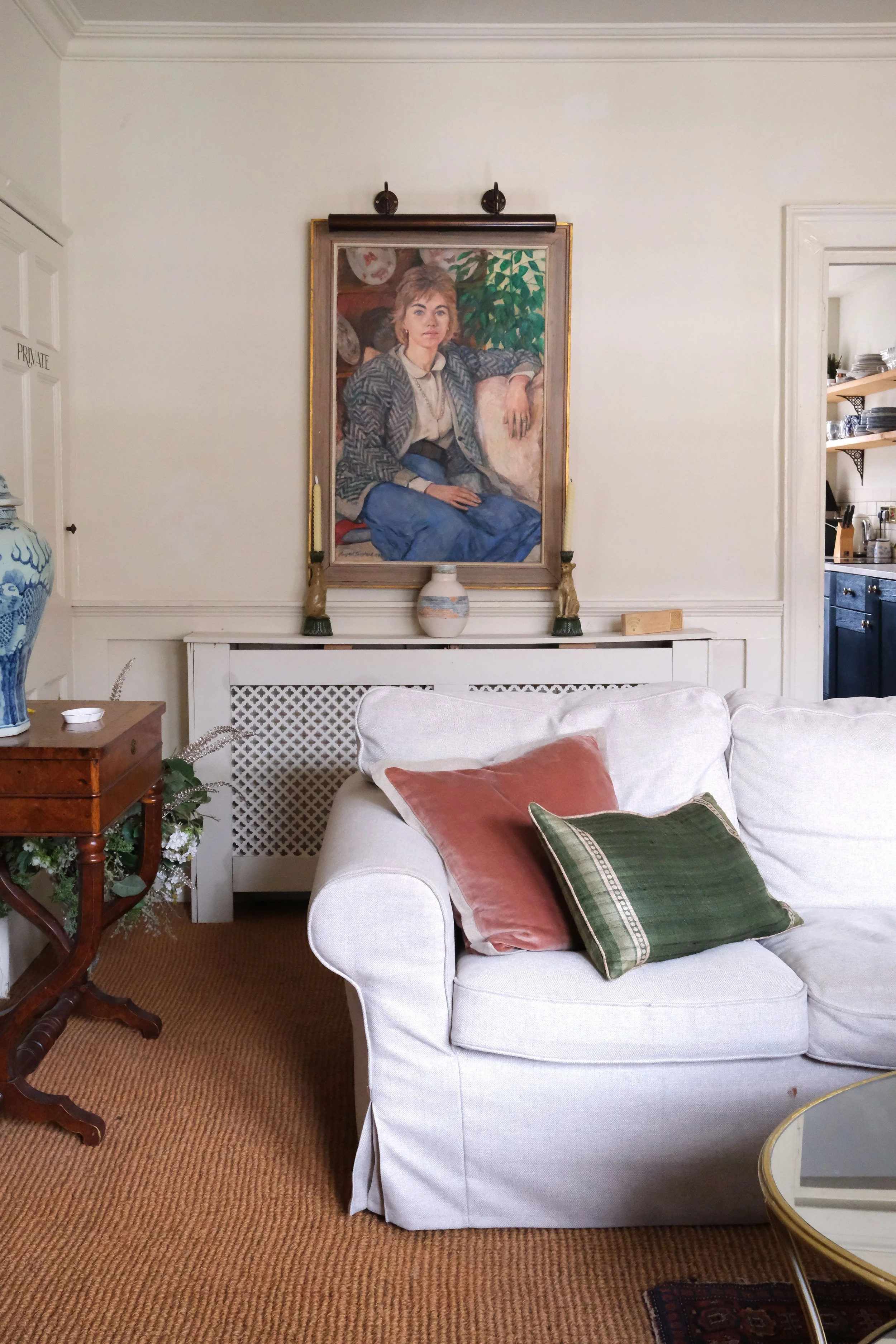 Collection of vintage paintings and gilt frames on the white walls of an English living room