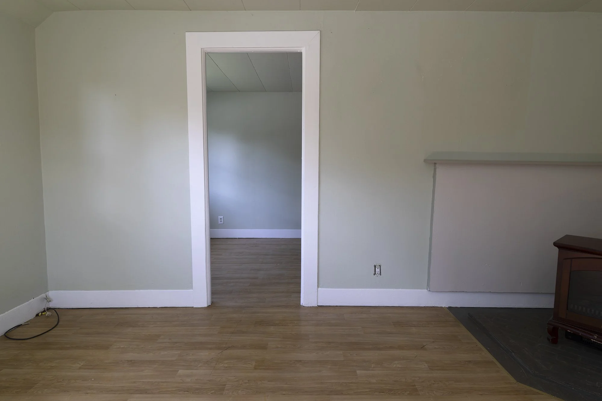 Before view from dining room toward bedroom showing pergo floors, electric heater, and original layout before doorway was moved
