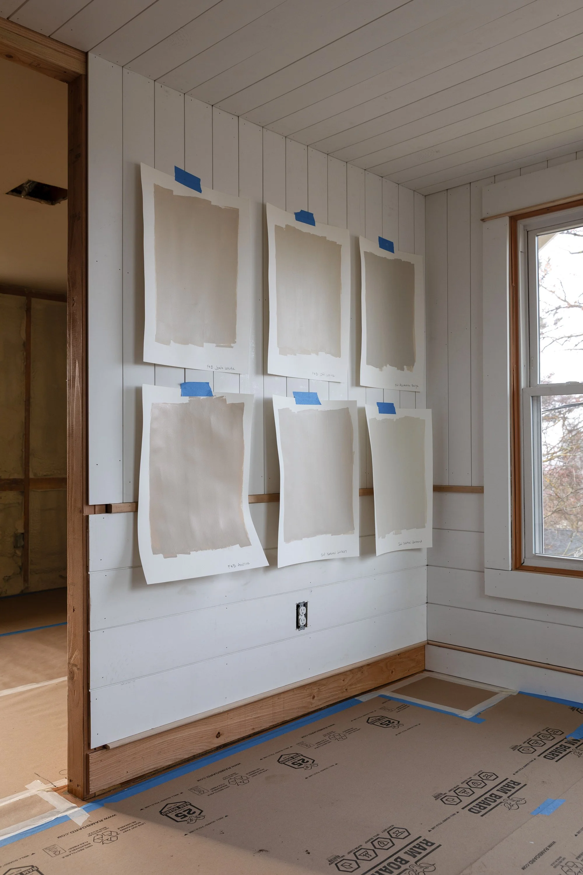 Angled view of six warm neutral paint samples on planked walls showing depth and undertone variation