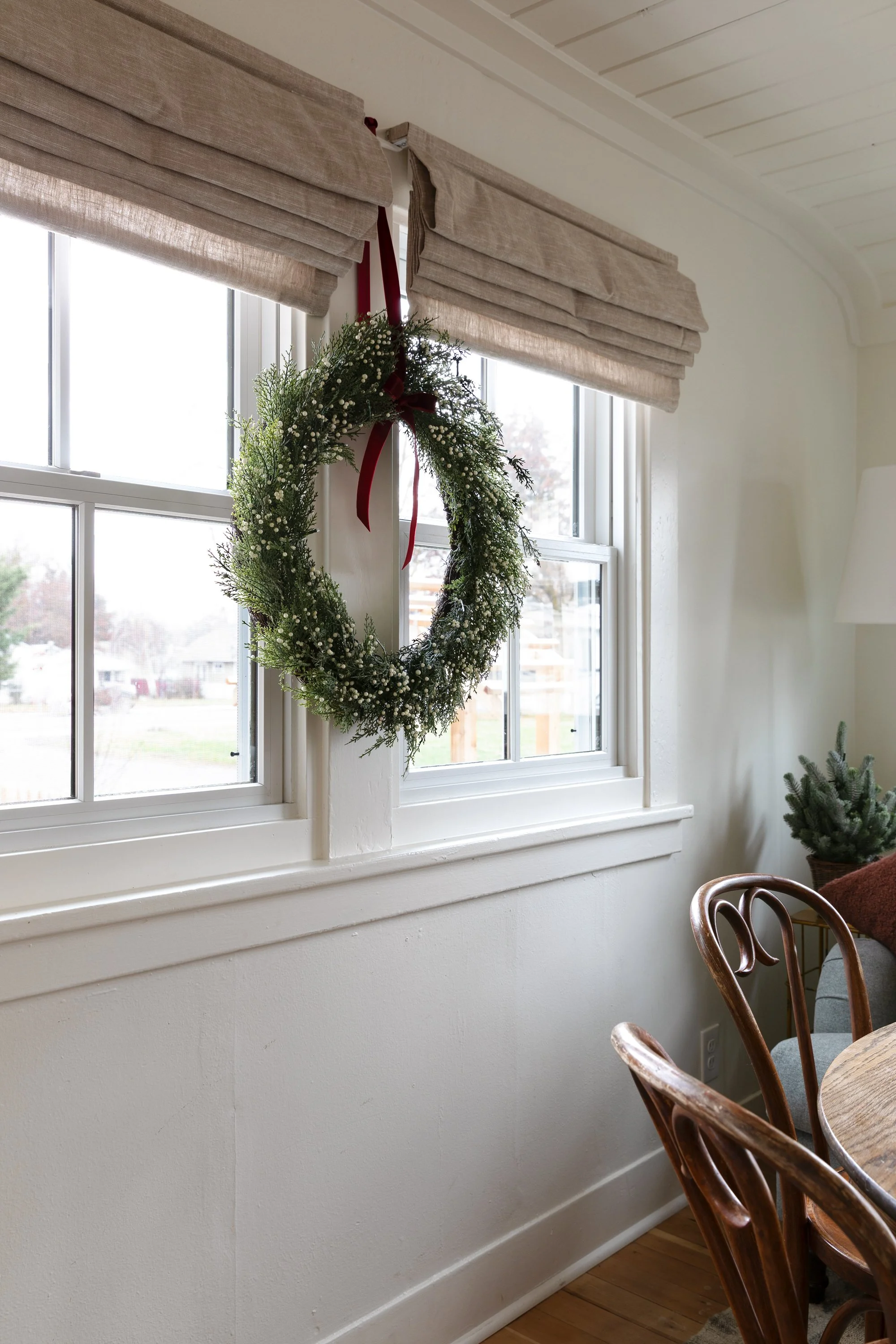 Faux holiday wreath hanging in the dining room window at the Poplar Cottage