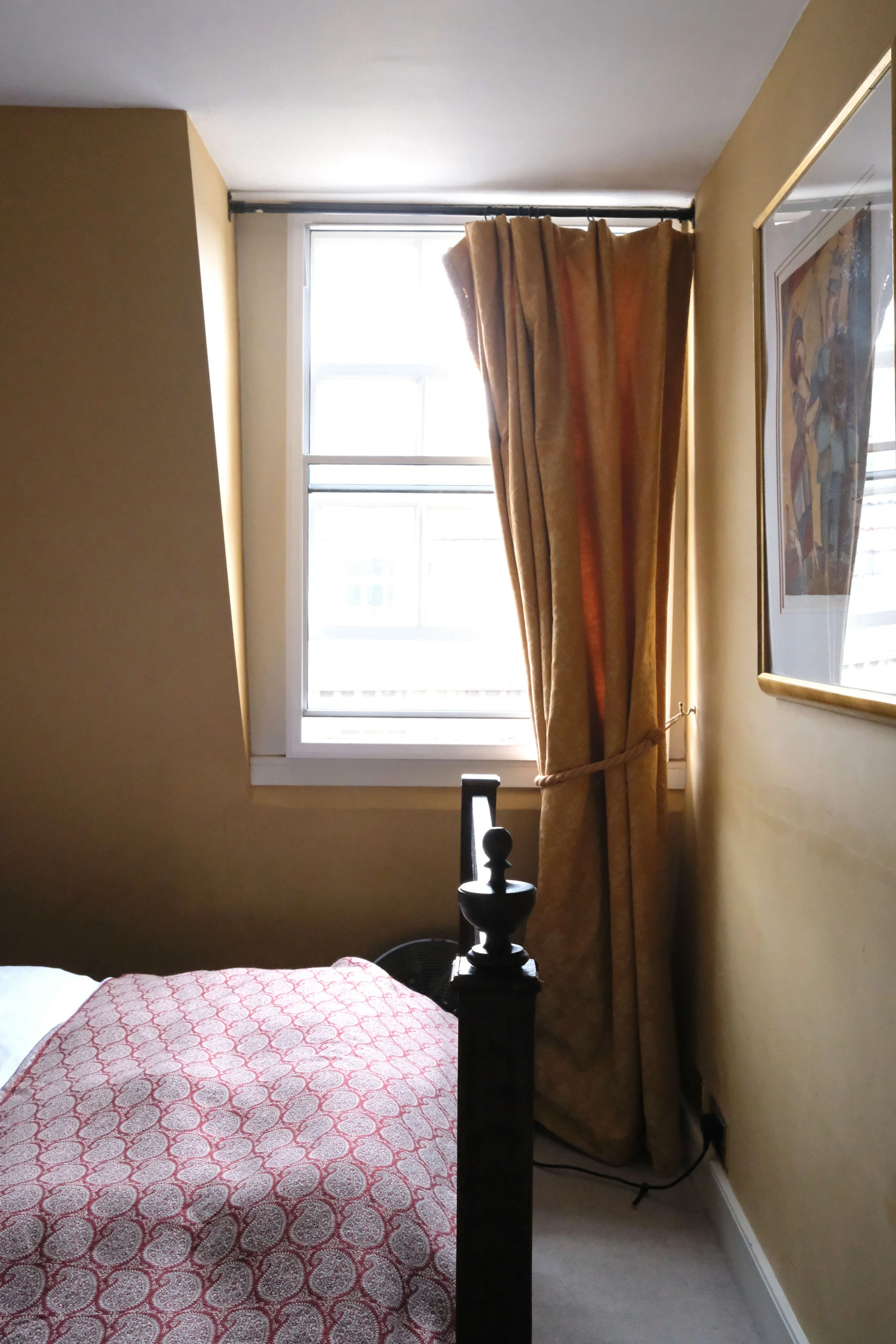 Vintage curtains, dark wood furniture, and warm yellow walls in an English bedroom