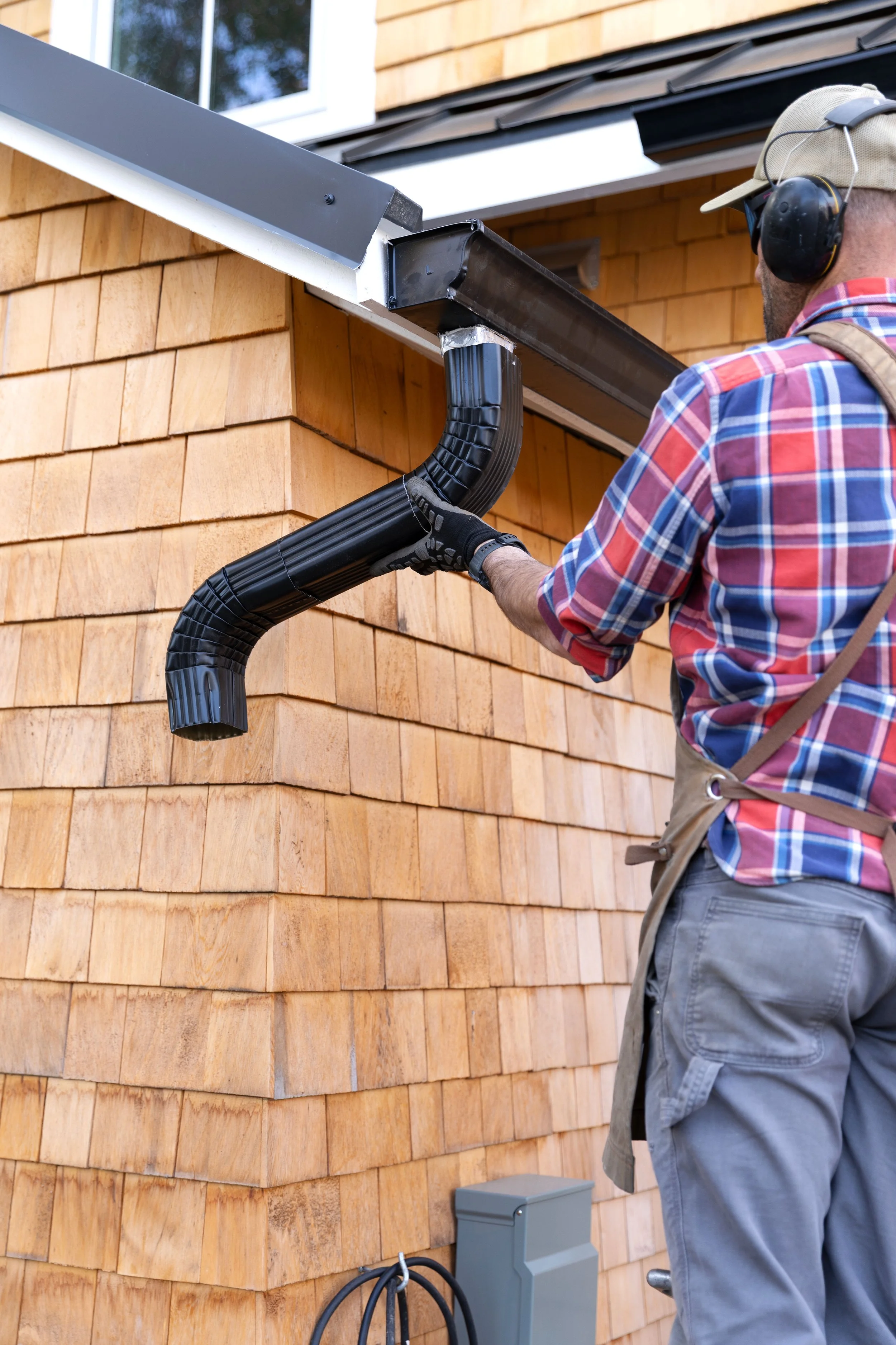 Adding a black metal downspout to DIY gutters at the Poplar Cottage