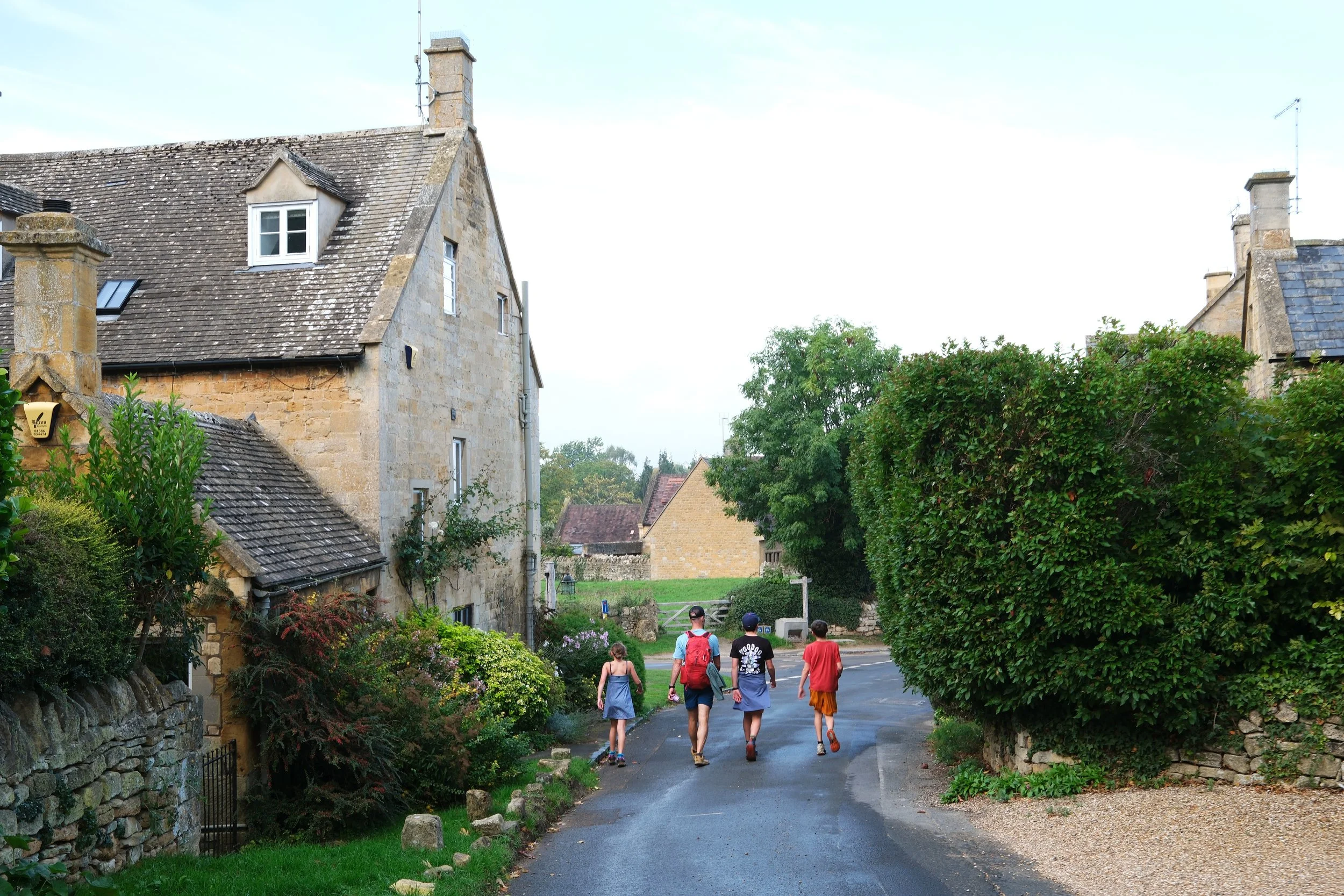 Family hiking the Cotswold Way through an old English village