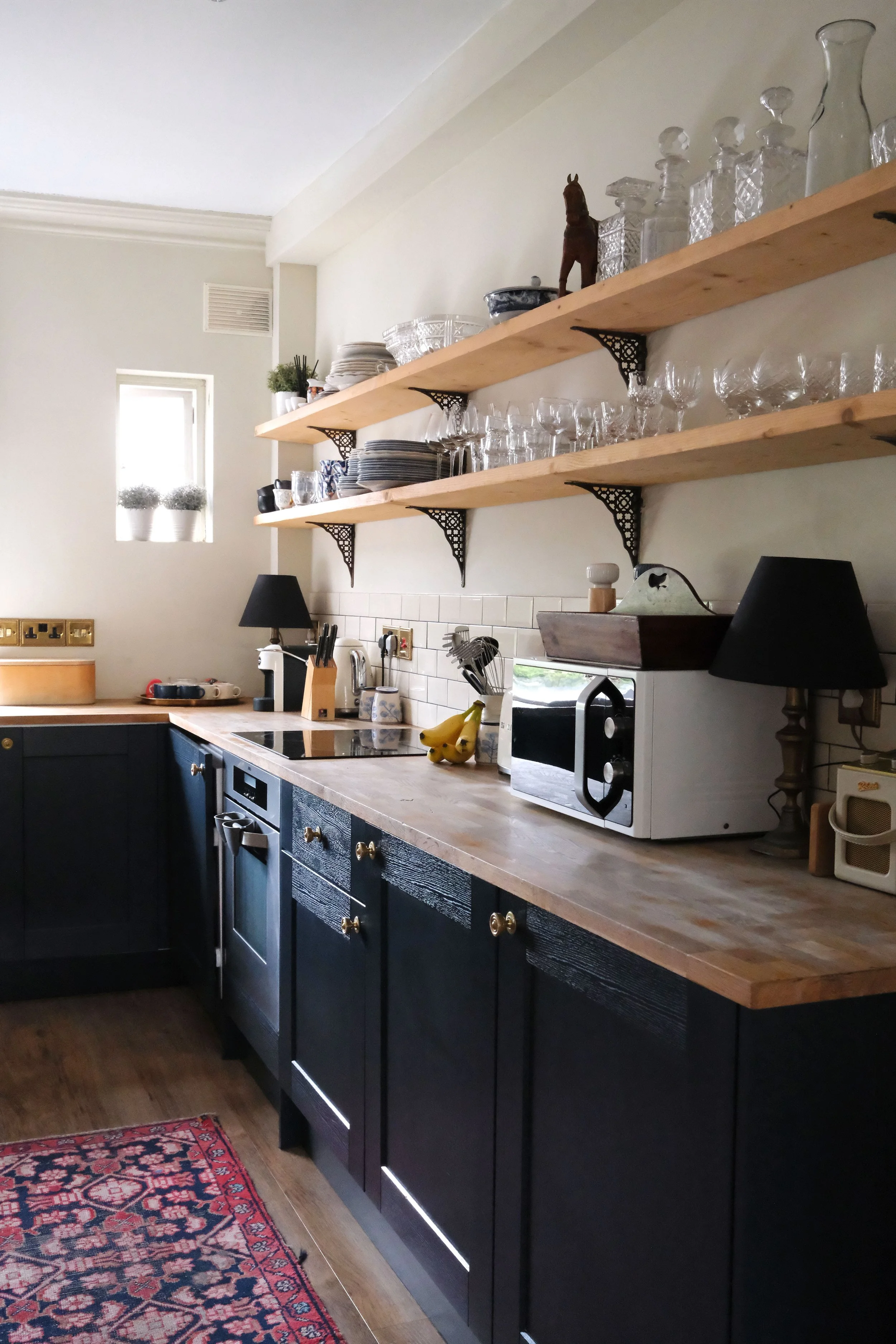 Character-filled Bath apartment kitchen with dark cabinetry, wood counters, and open shelving