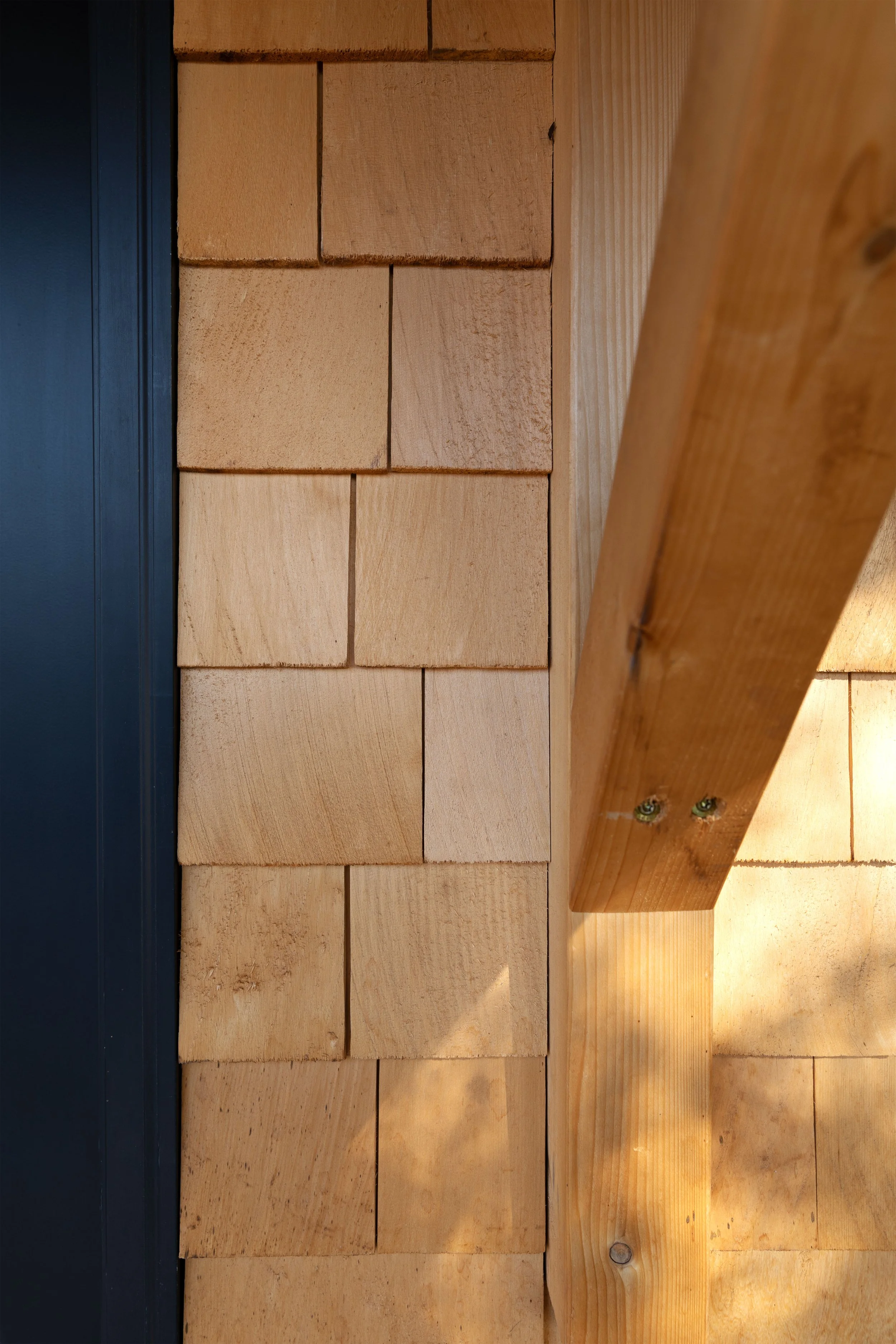 Close up of cedar shake siding and black door trim on the Poplar Cottage