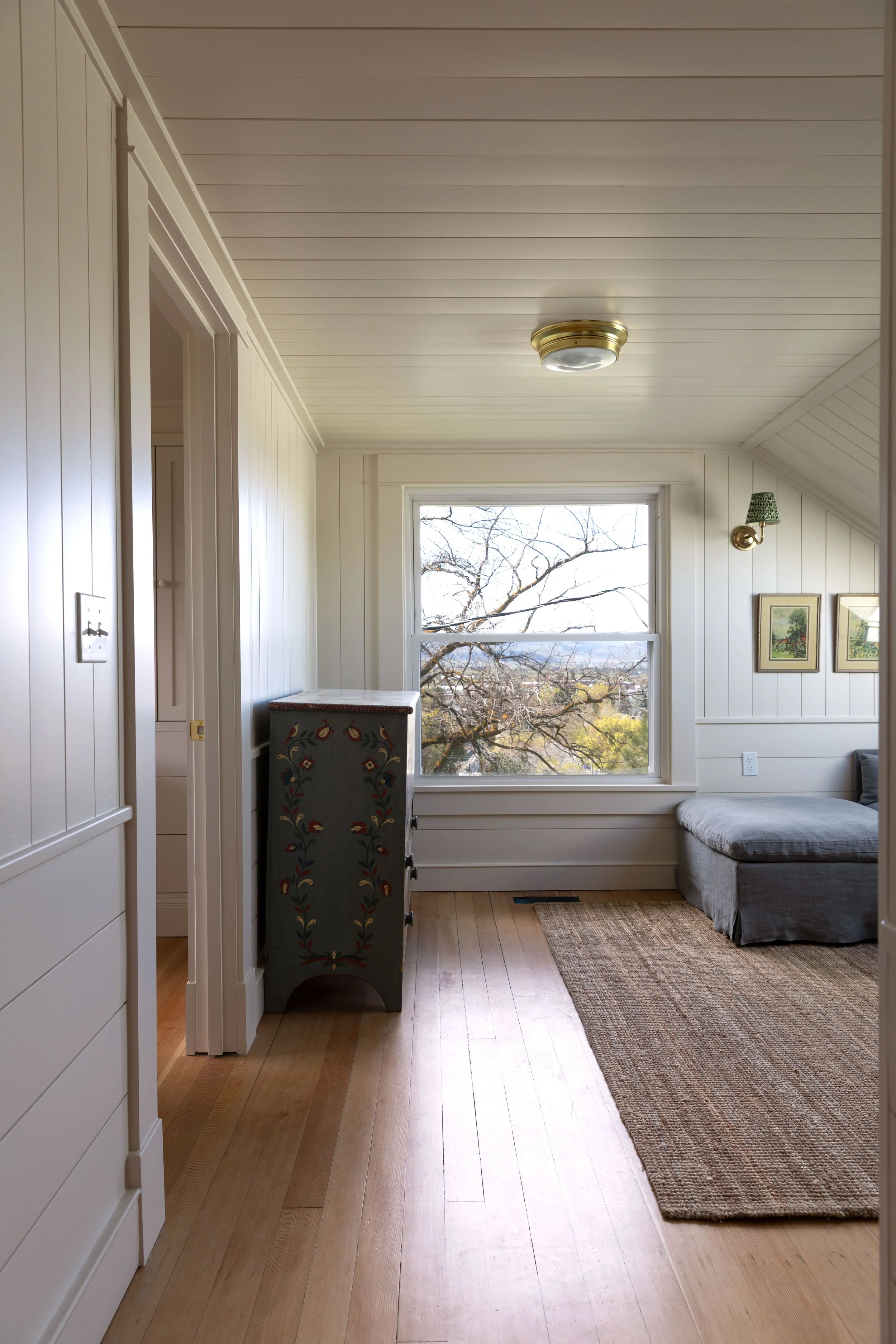 Cozy small living room in an old house with low ceilings, layered lighting, and warm neutral textures