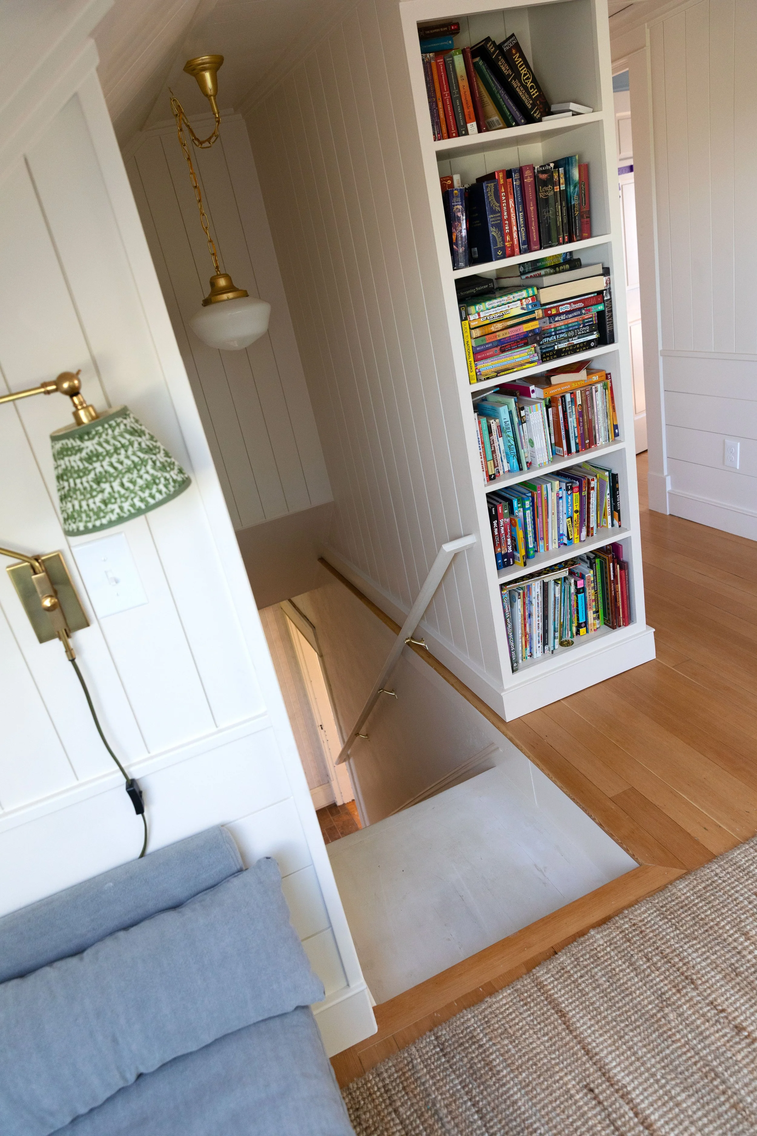 Floor-to-ceiling built-in bookcase serving as a stair guard on an old-house landing