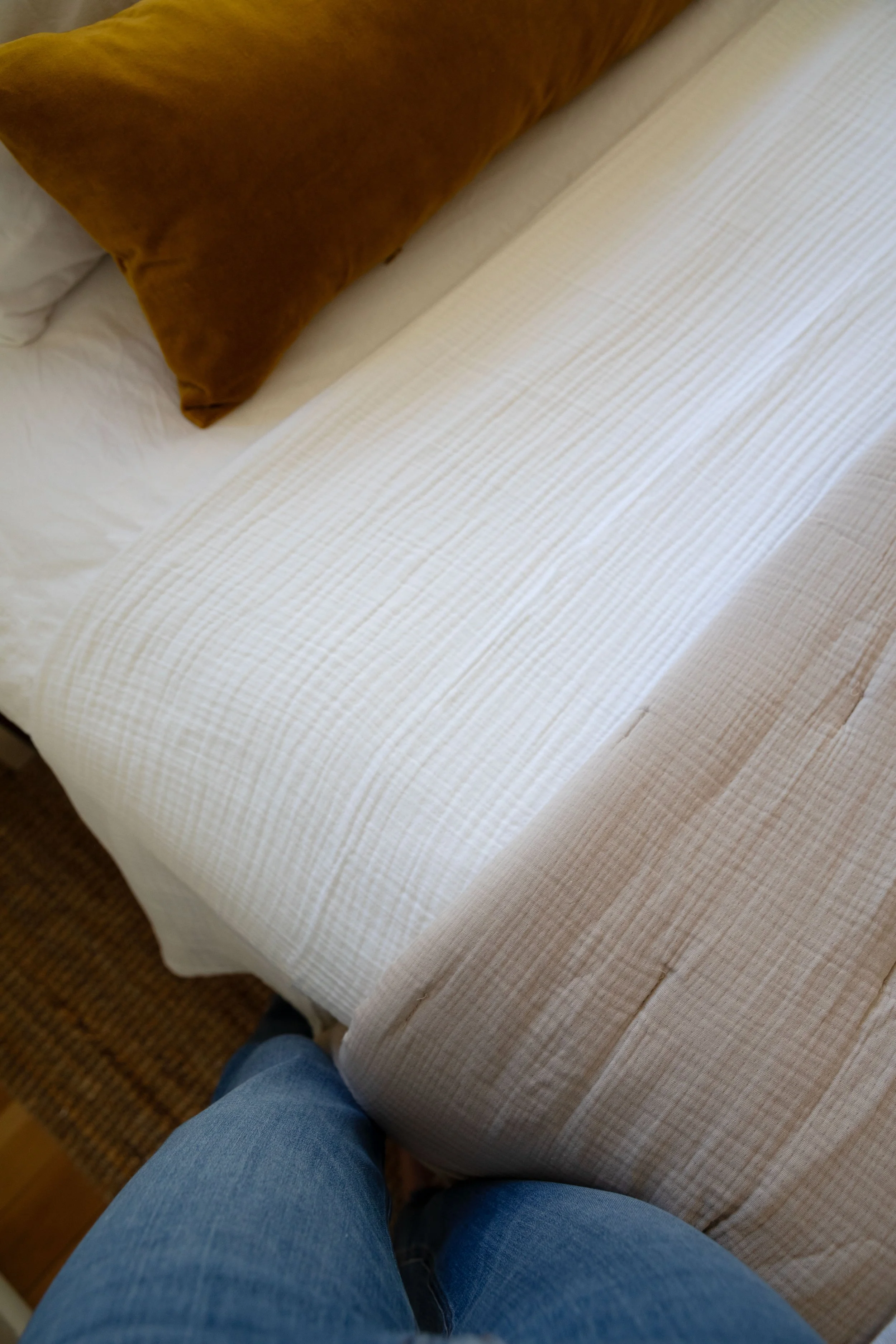 Layered cotton bedding with airy white blanket and gauzy quilt in a cozy cottage bedroom