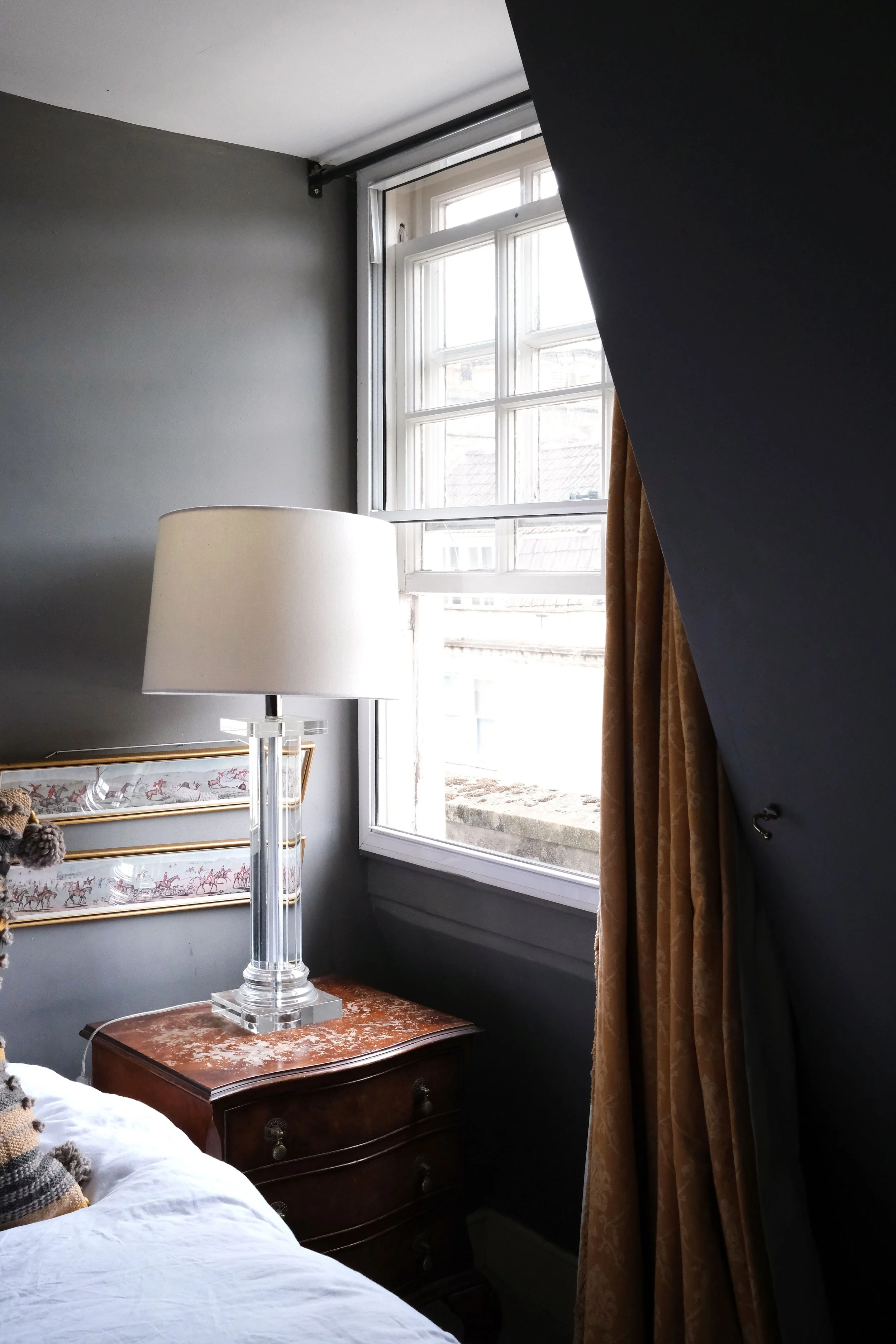 Soft gray bedroom with antique portraits, brass details, and dark wood furniture