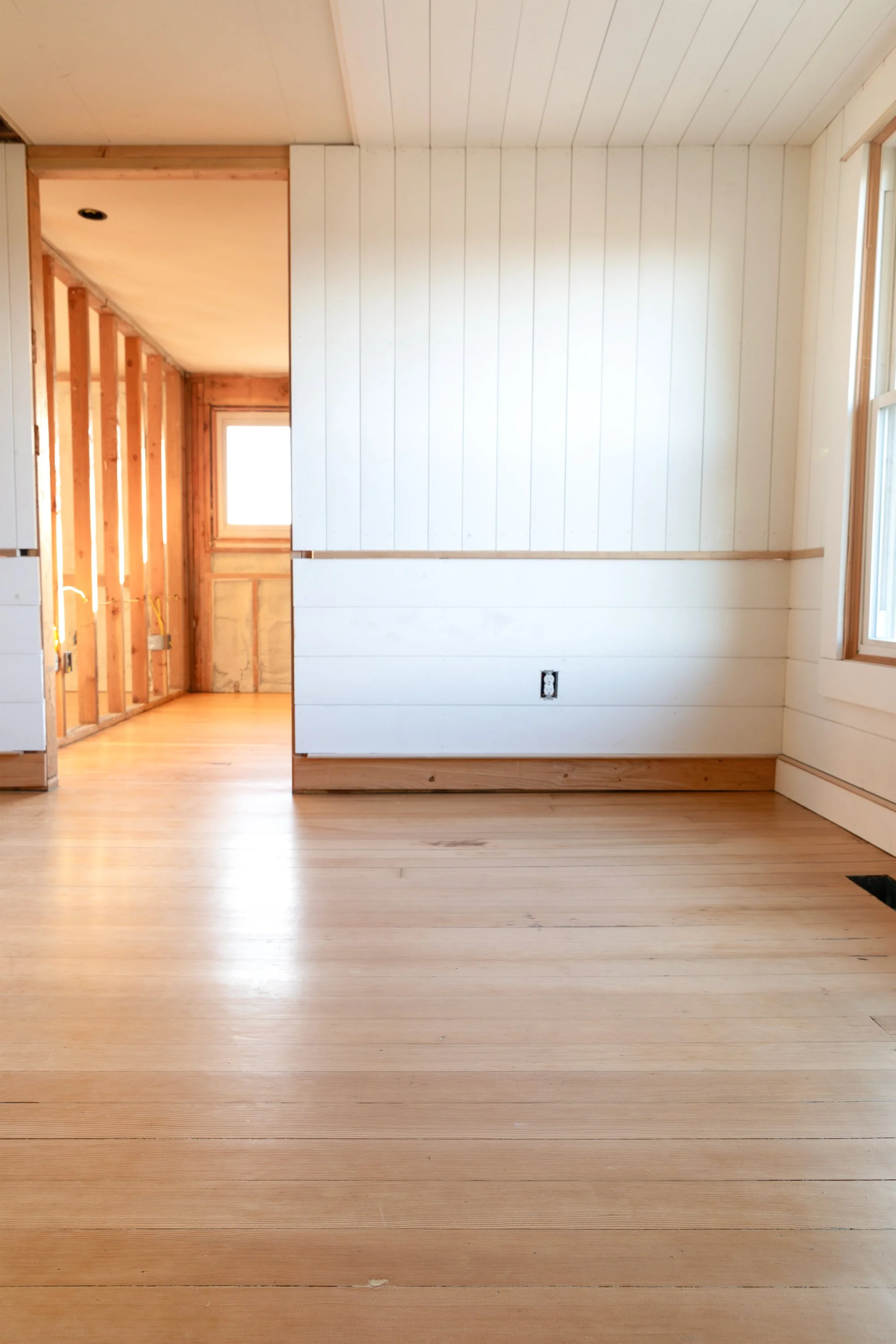 Finished fir floors leading into bedroom at the Hill House with paneled walls