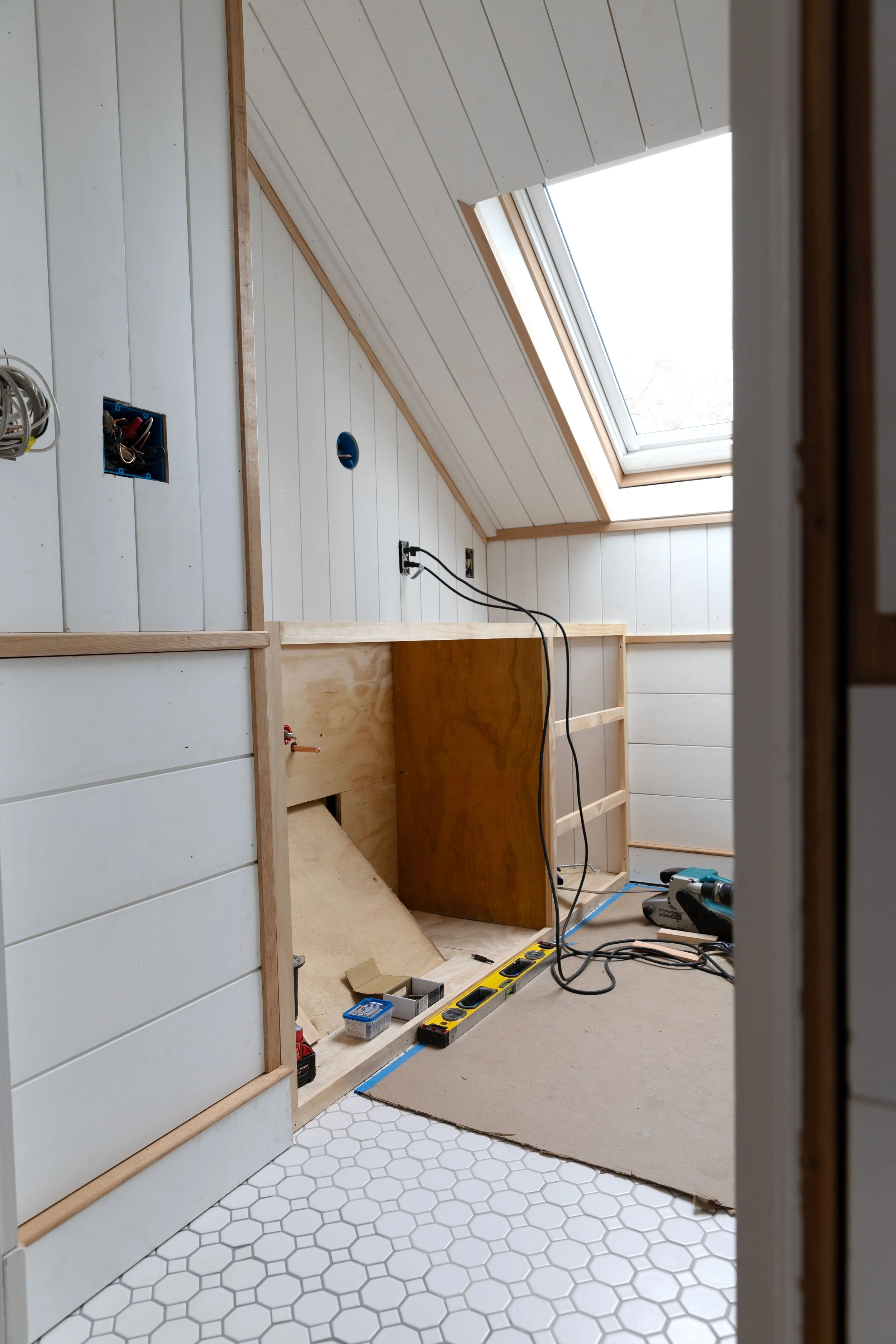 Angled bathroom view showing vanity construction and visible epoxy grout color variation on floor tiles