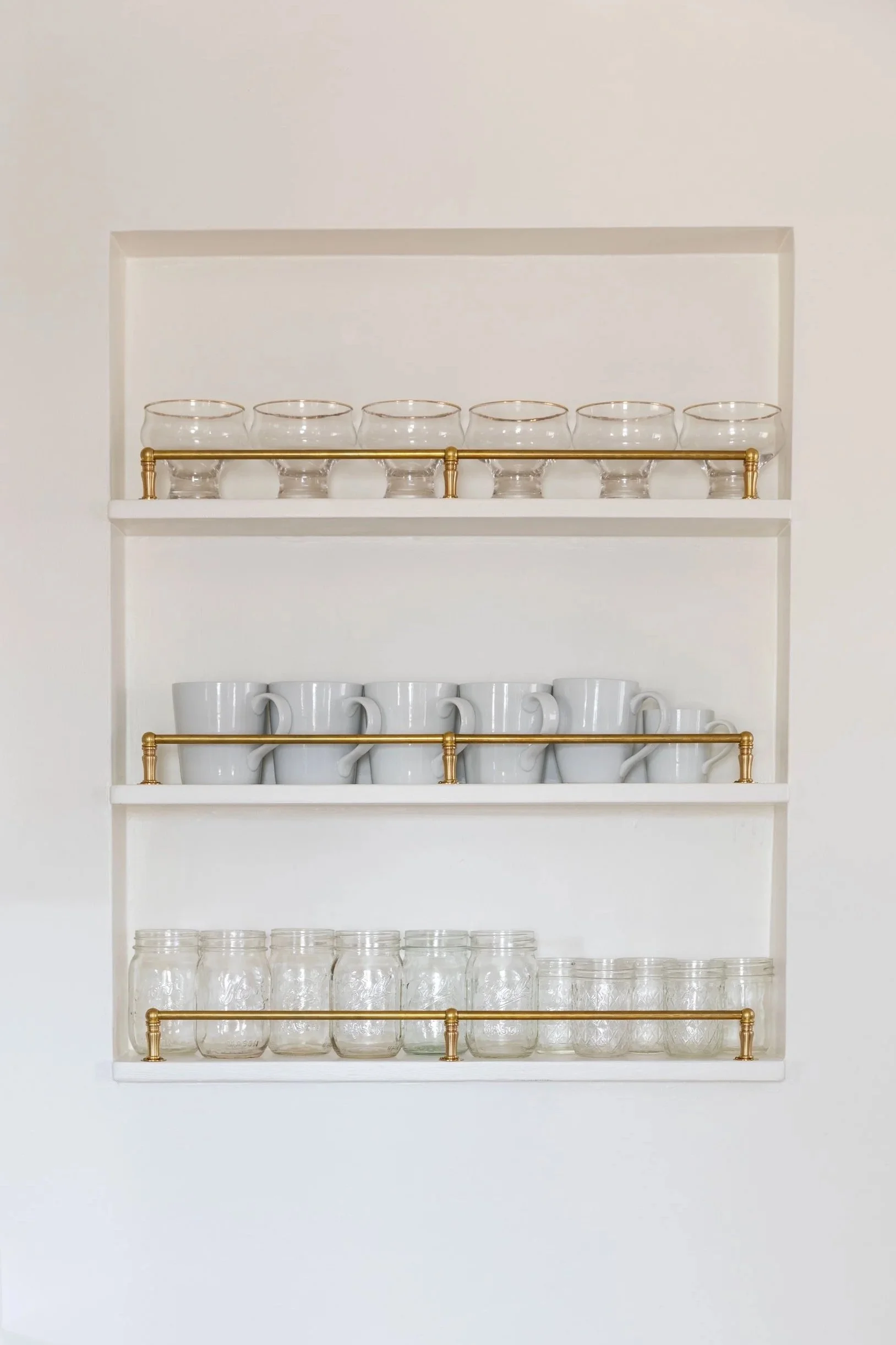 Close-up of recessed kitchen shelf with gallery rail and glassware.