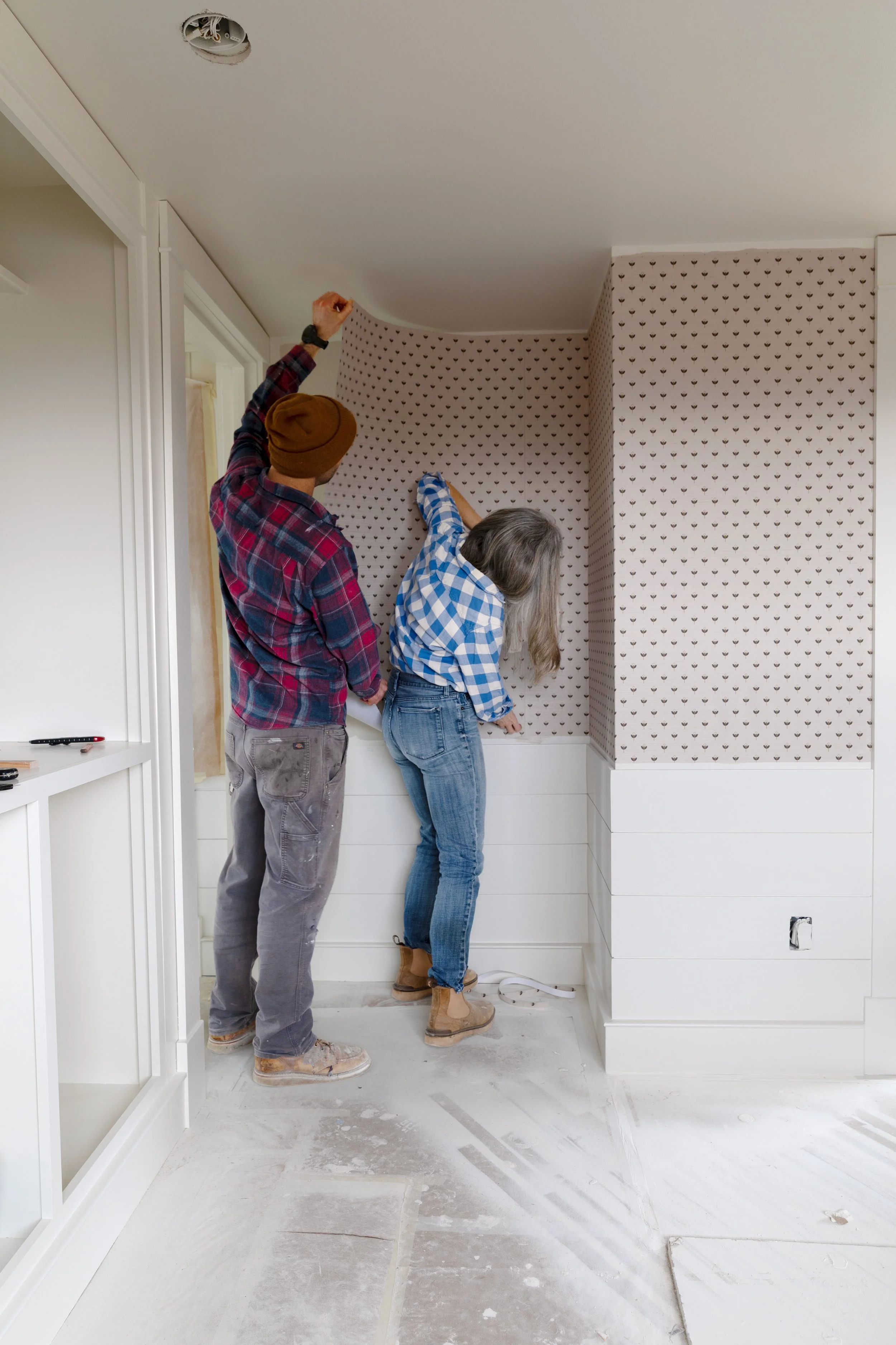 Installing grasscloth wallpaper together in a bedroom renovation at the Hill House