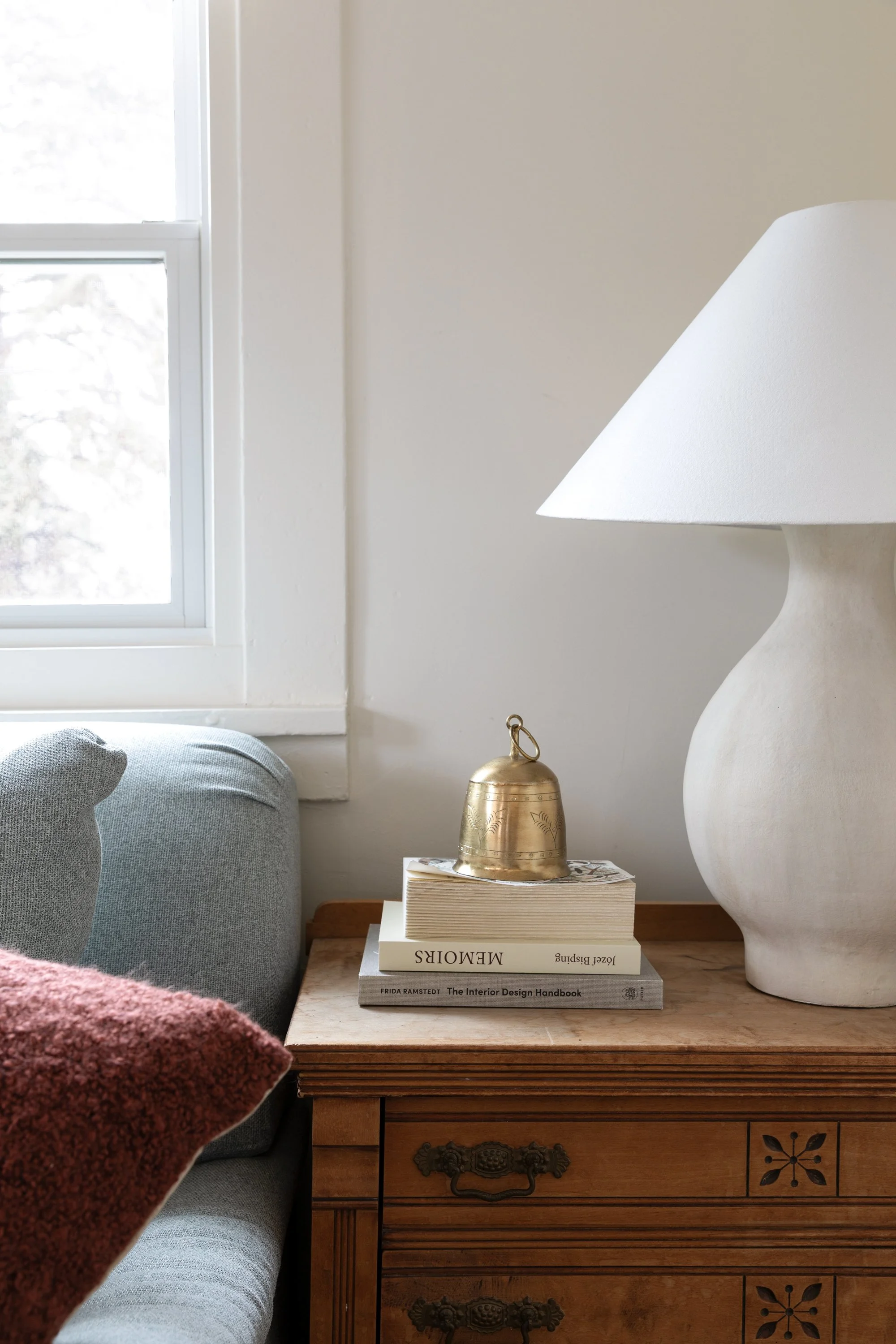 Brass bell holiday decor styled on books in the Poplar Cottage dining room