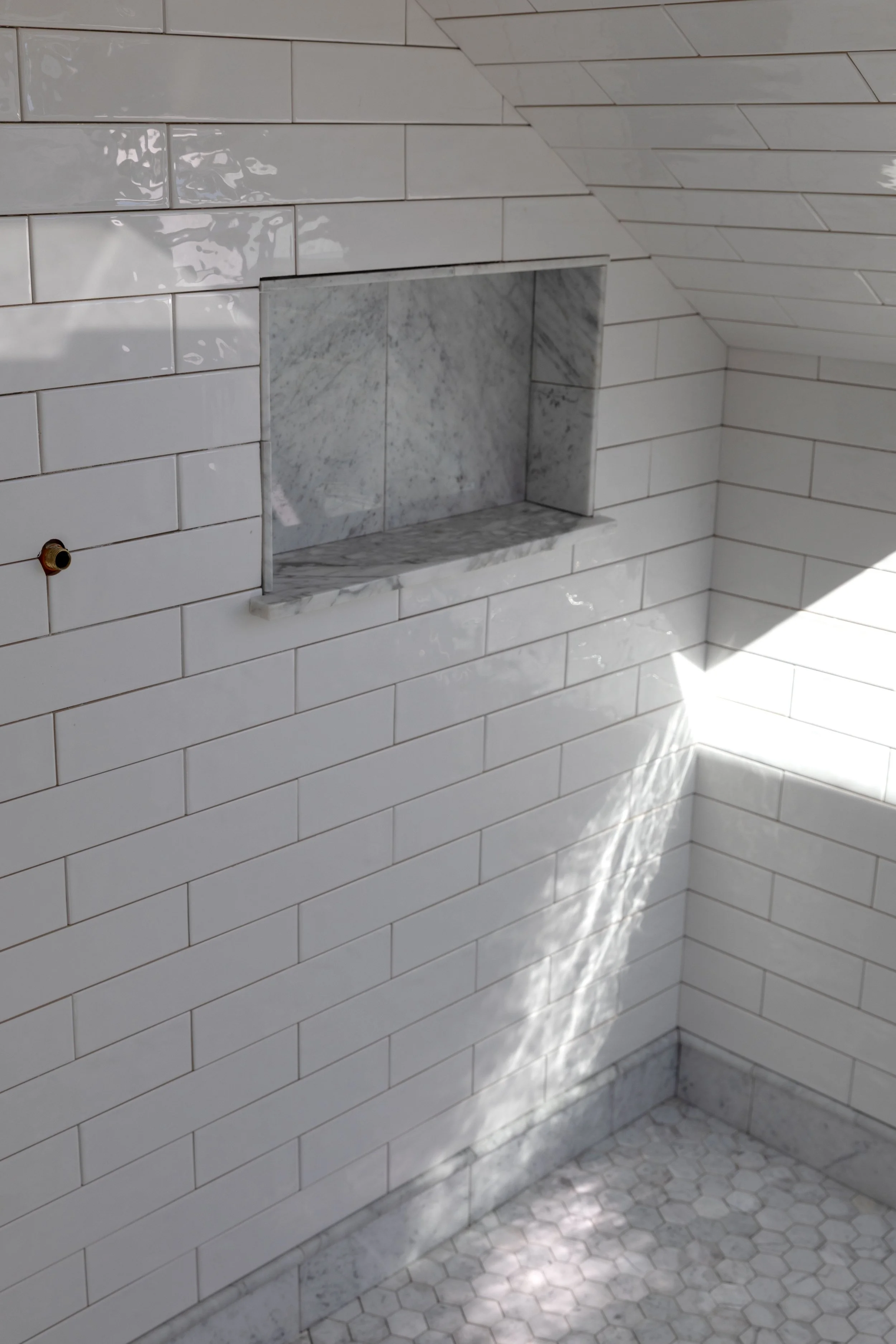 White subway walls with a marble shower niche