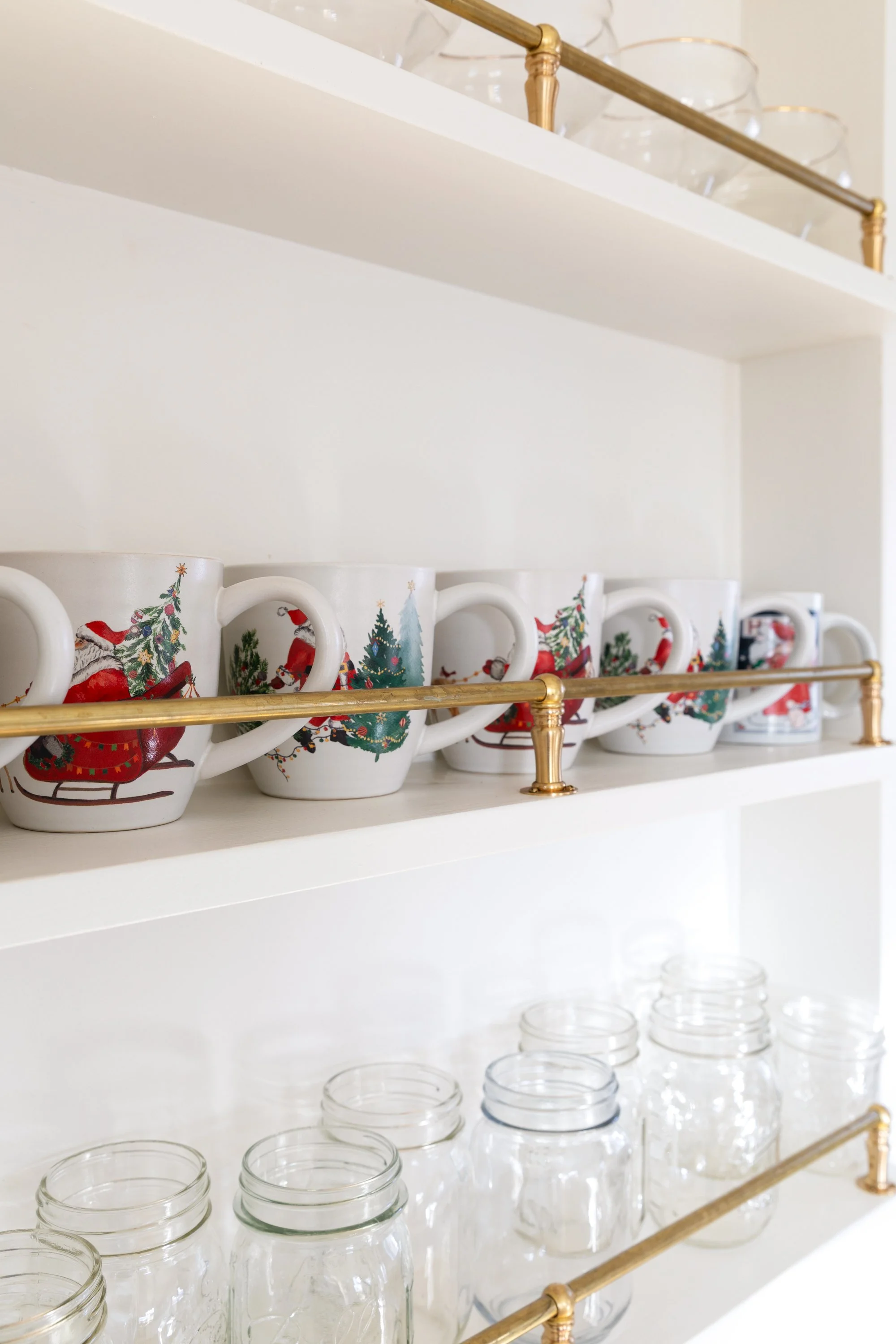 Holiday mugs displayed on shelves with unlacquered brass gallery rail