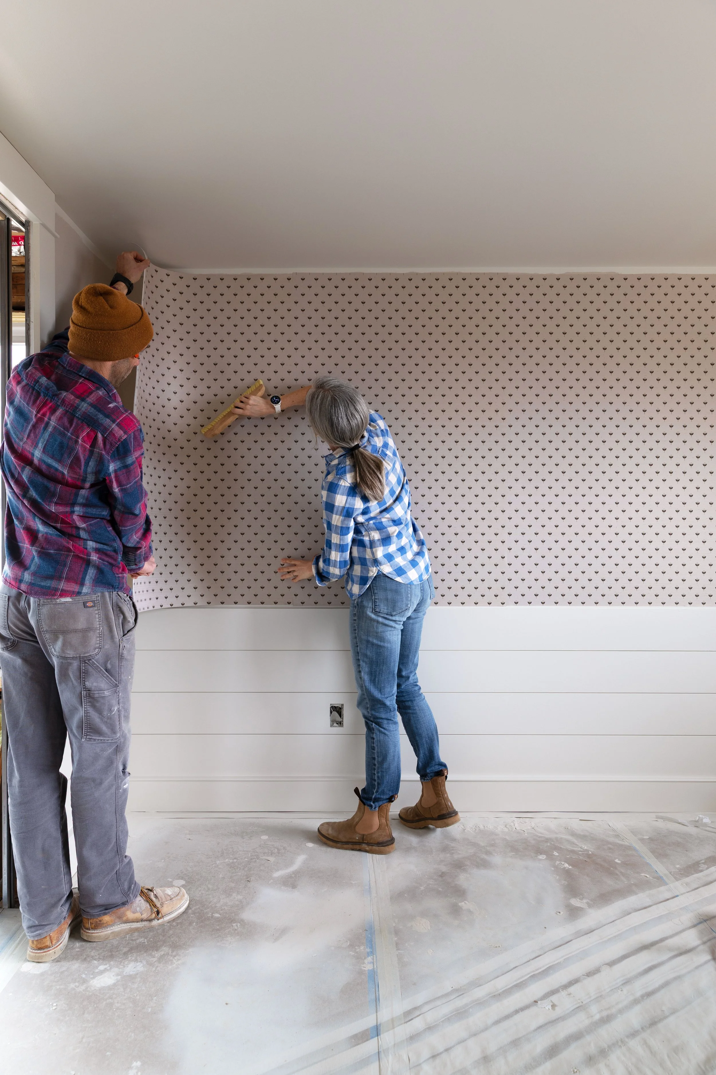 Installing grasscloth wallpaper together in a bedroom renovation at the Hill House