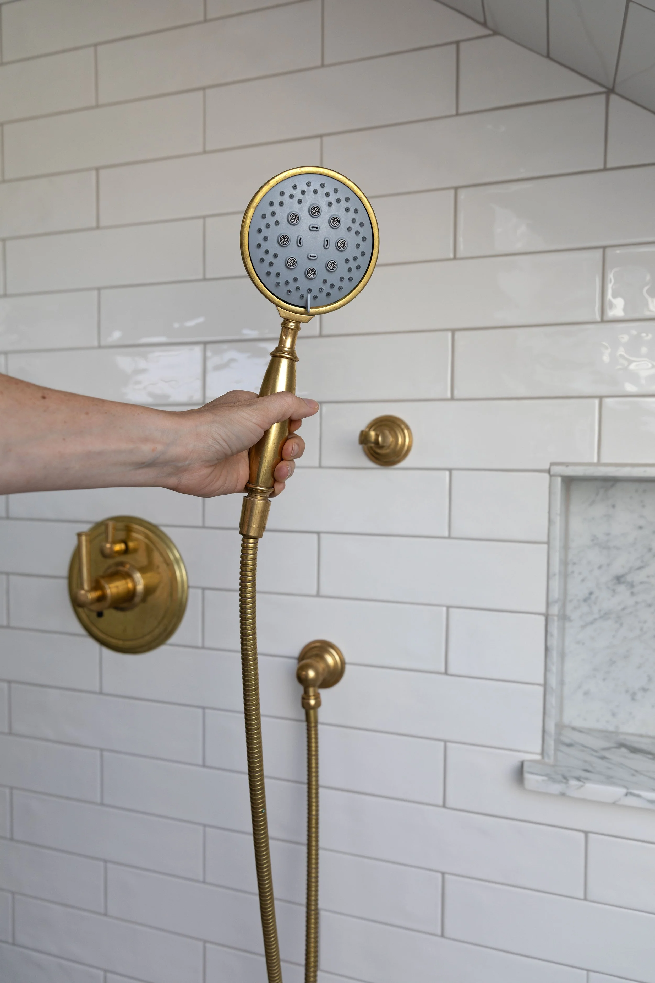 A handheld brass shower head in the Hill House ensuite bathroom