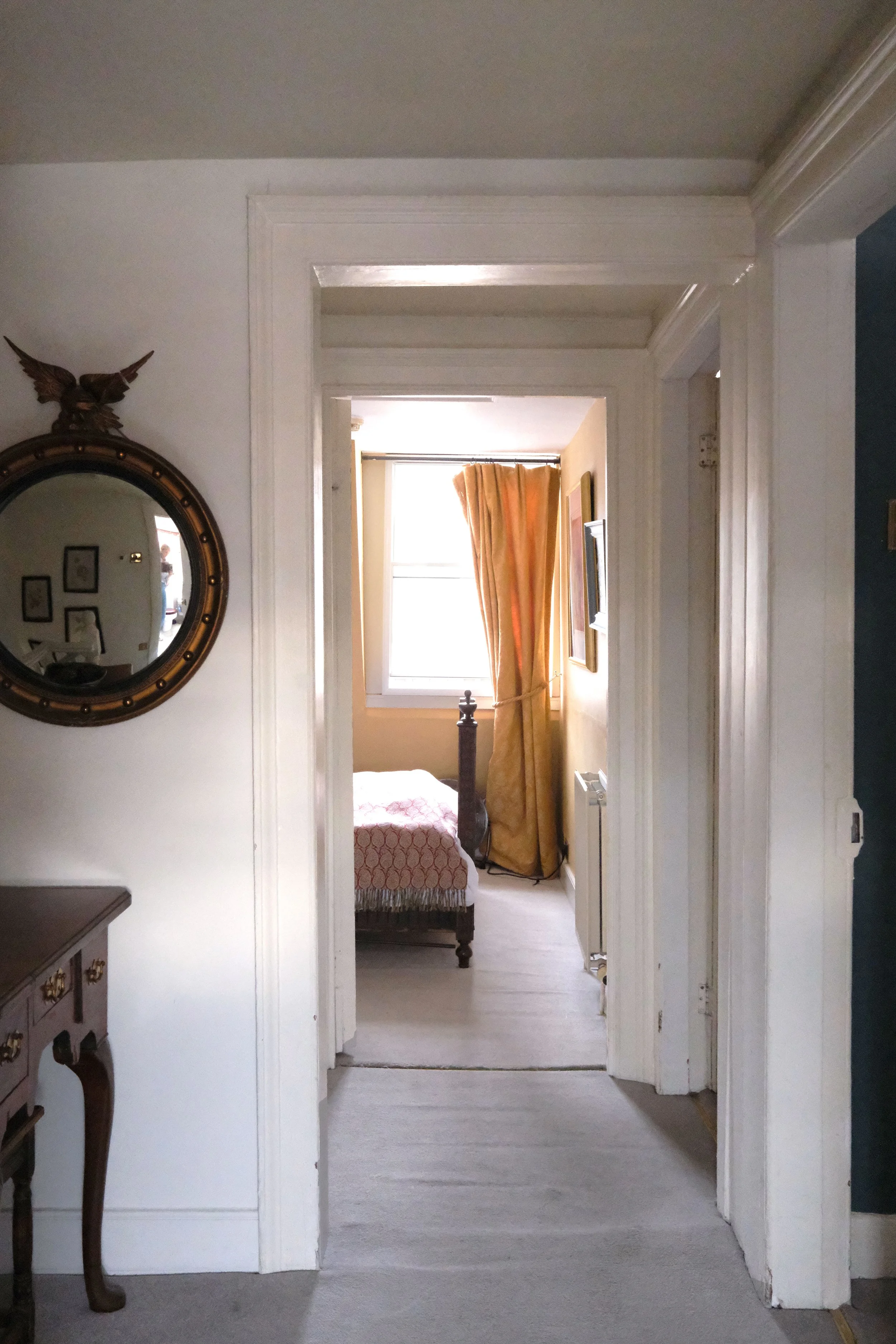Warm ochre bedroom with antique furniture, vintage art, and patterned curtains in Bath