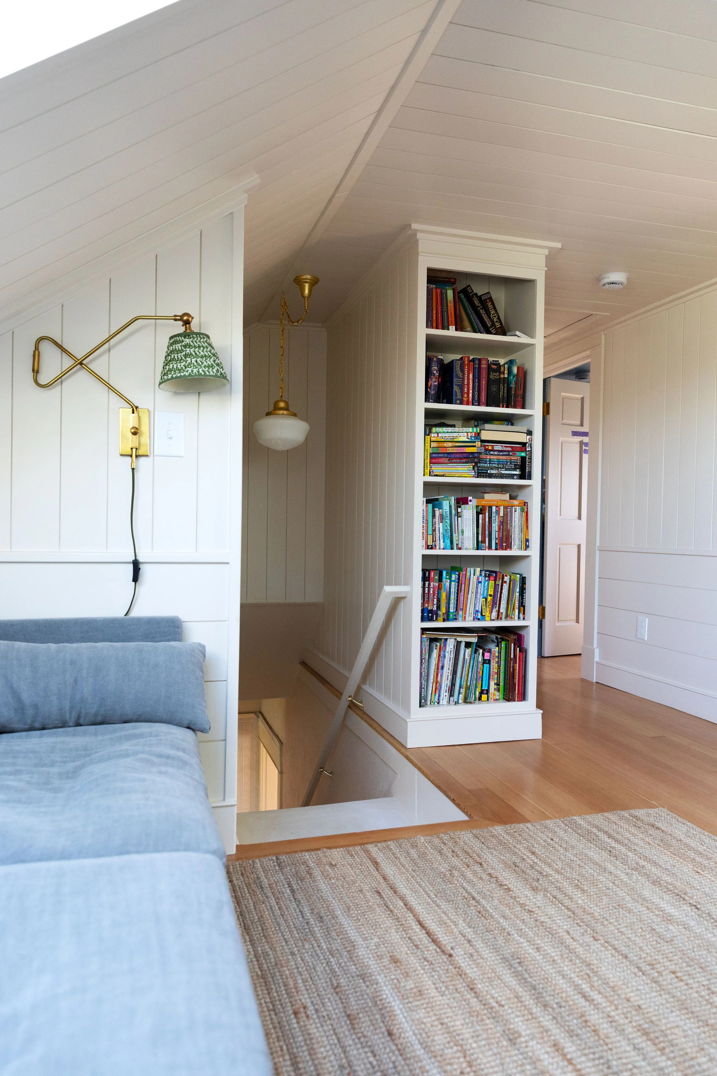 Finished upstairs landing and snug with sectional, skylight, woven shade, and wood floors