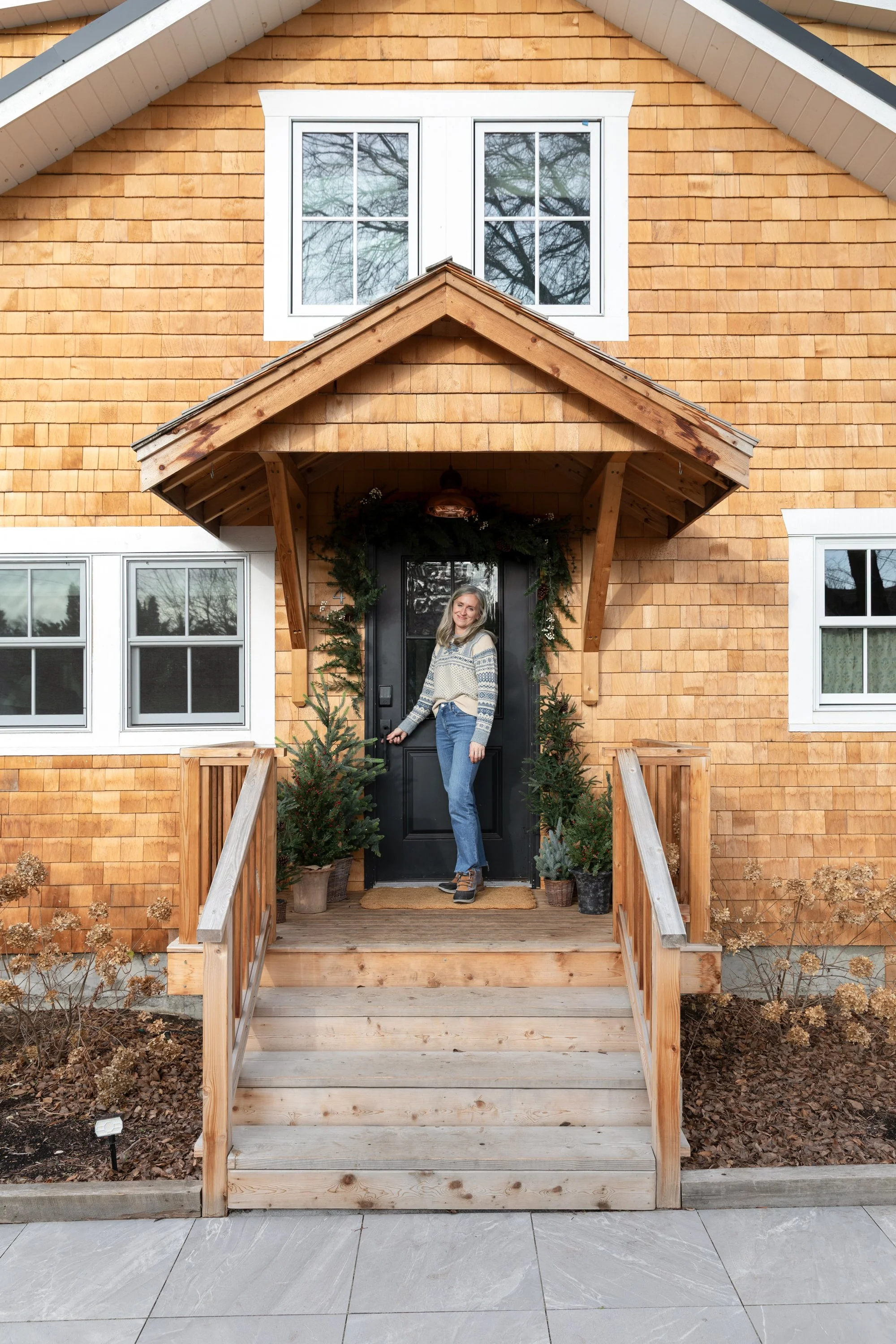 Cathy standing at the Poplar Cottage front door decorated with garland and faux trees