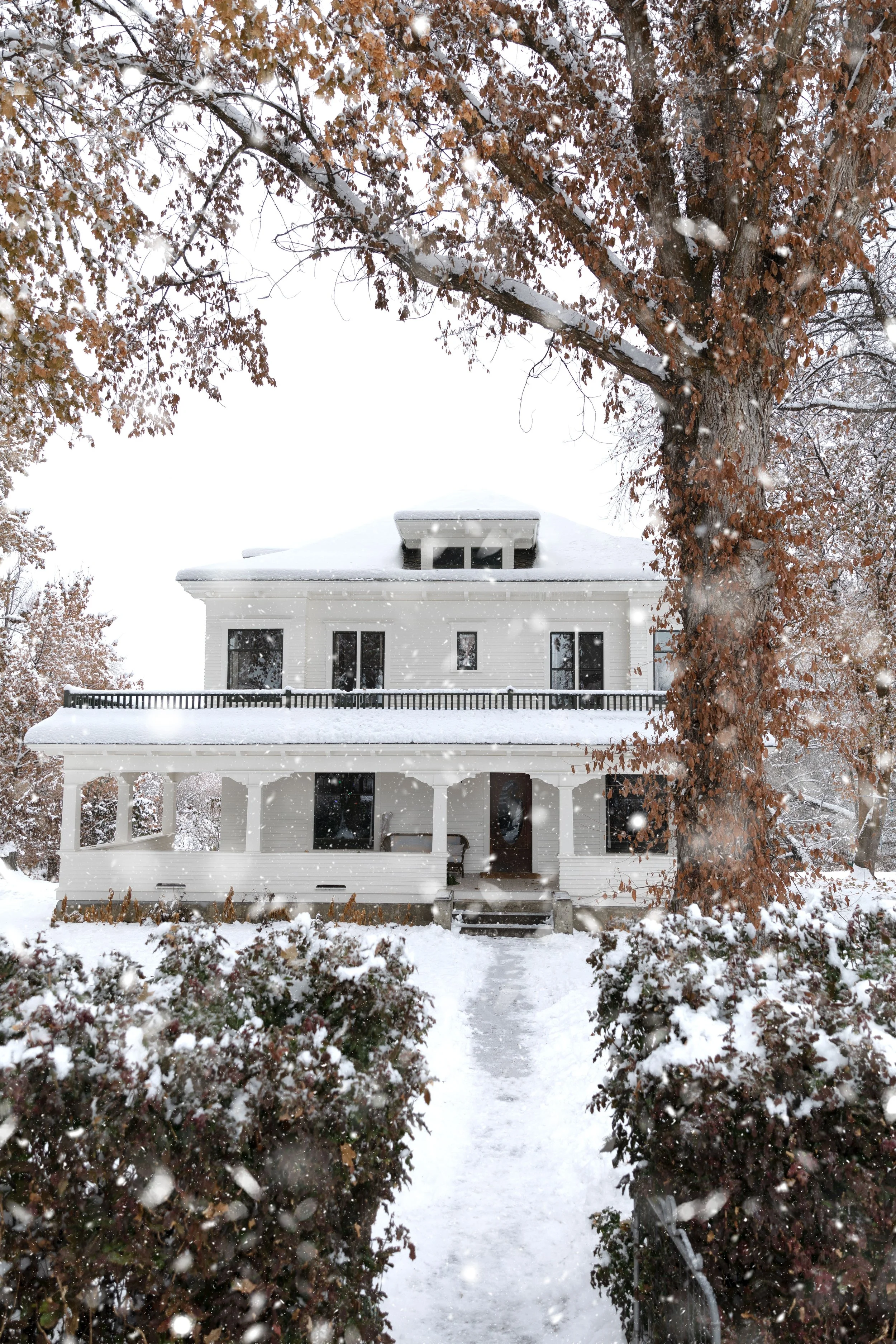 Farmhouse exterior with snow — welcoming old-house Christmas curb appeal.