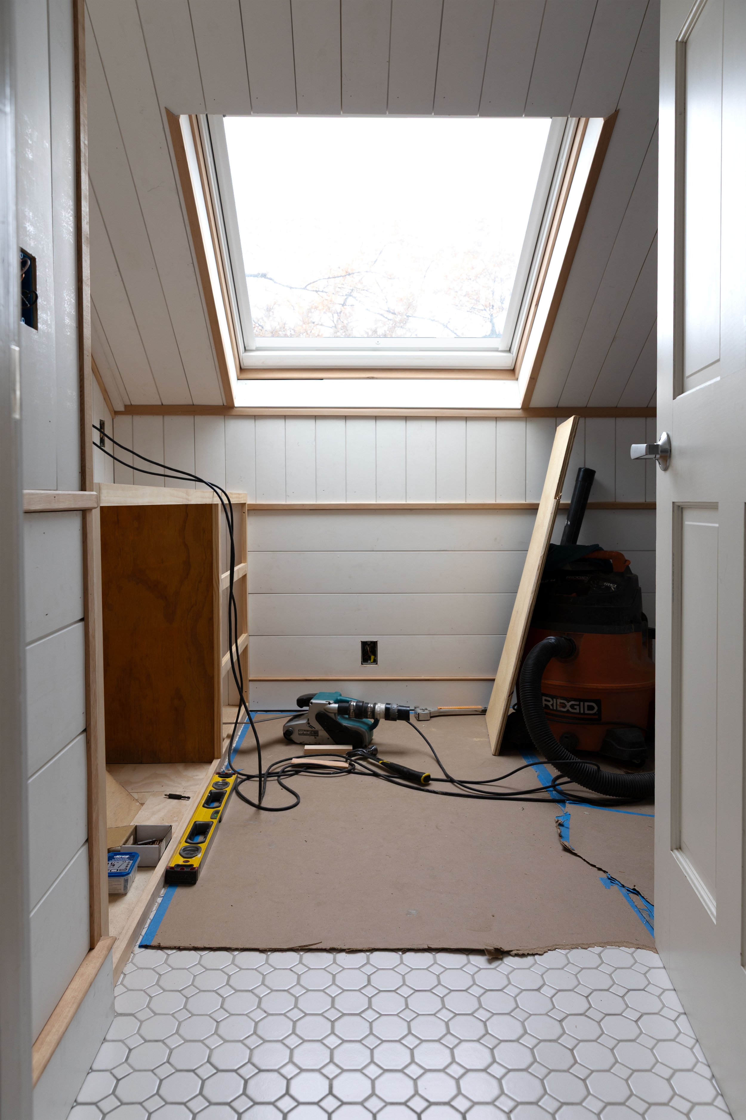 Wide view of bathroom with skylight showing epoxy grout color variation during renovation