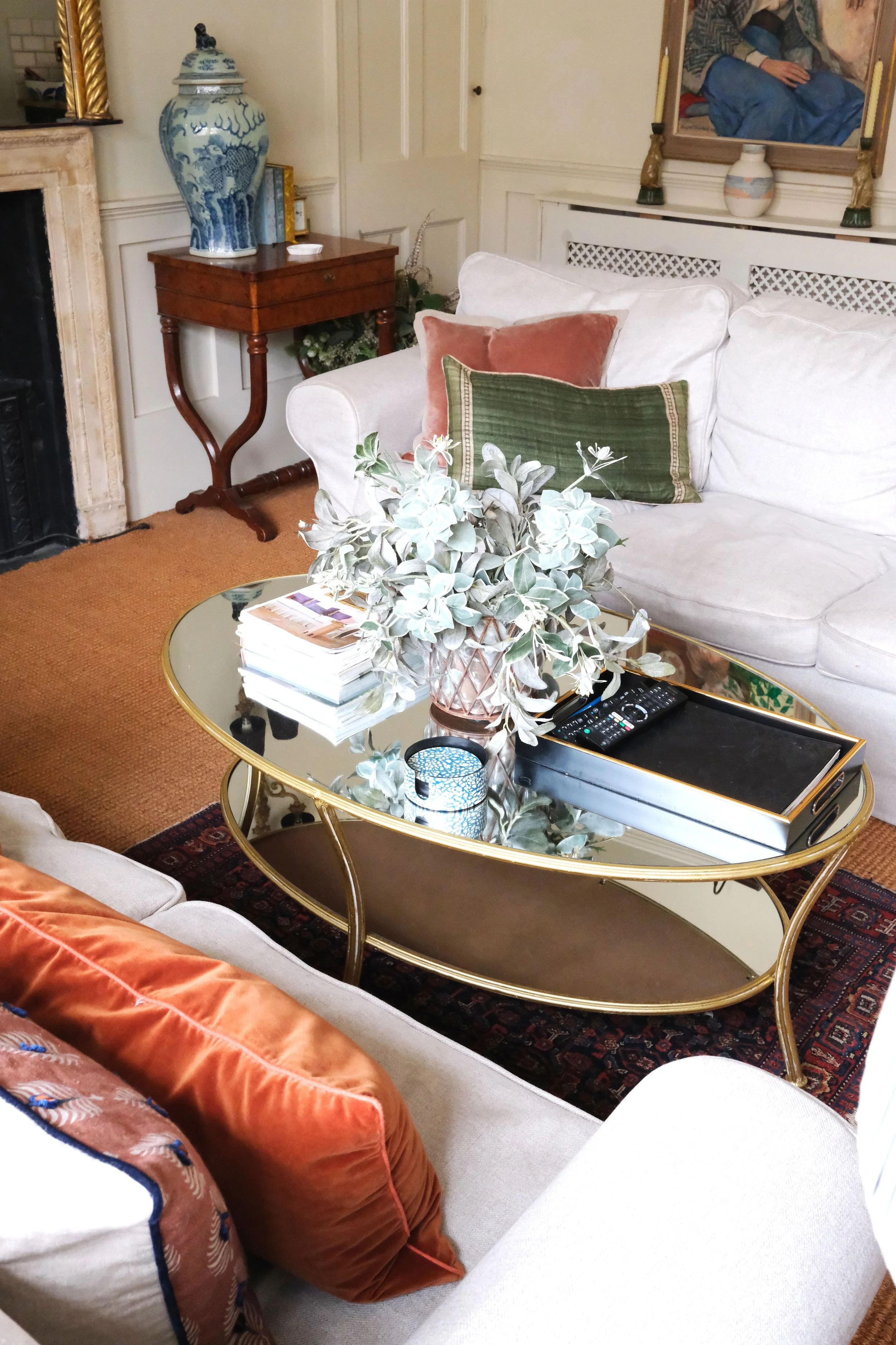Comfortable white sofa surrounded by vintage paintings, books, brass lighting, and antique furniture