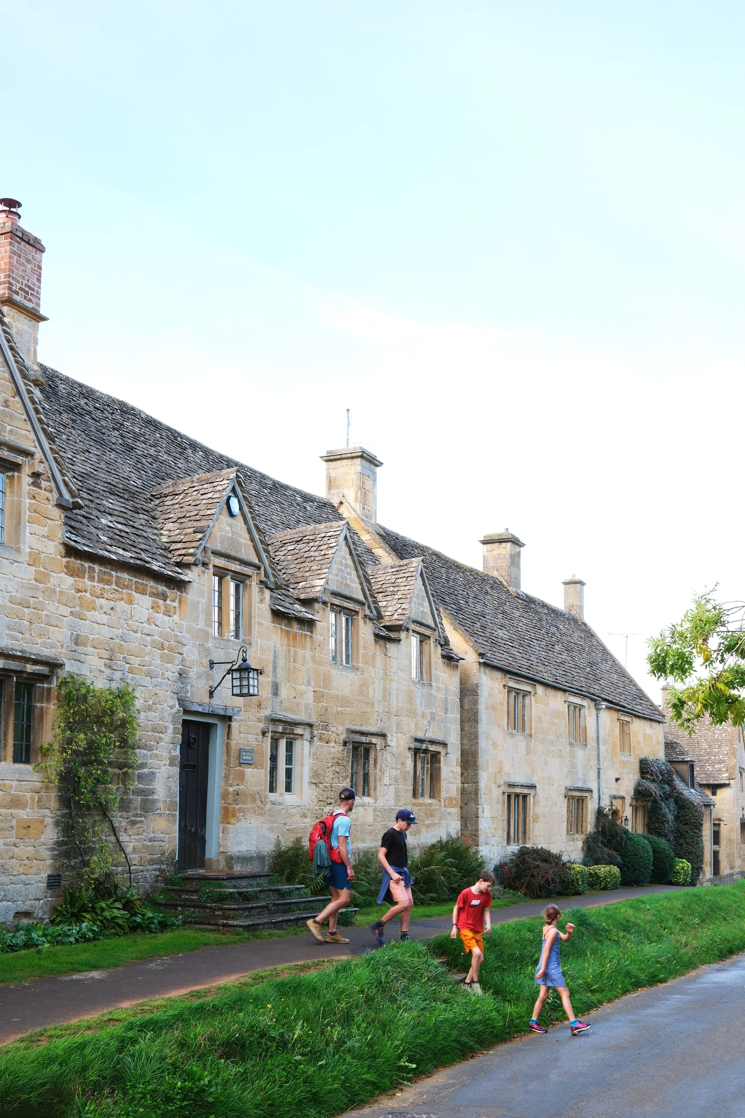 Family hiking the Cotswold Way through tan English village