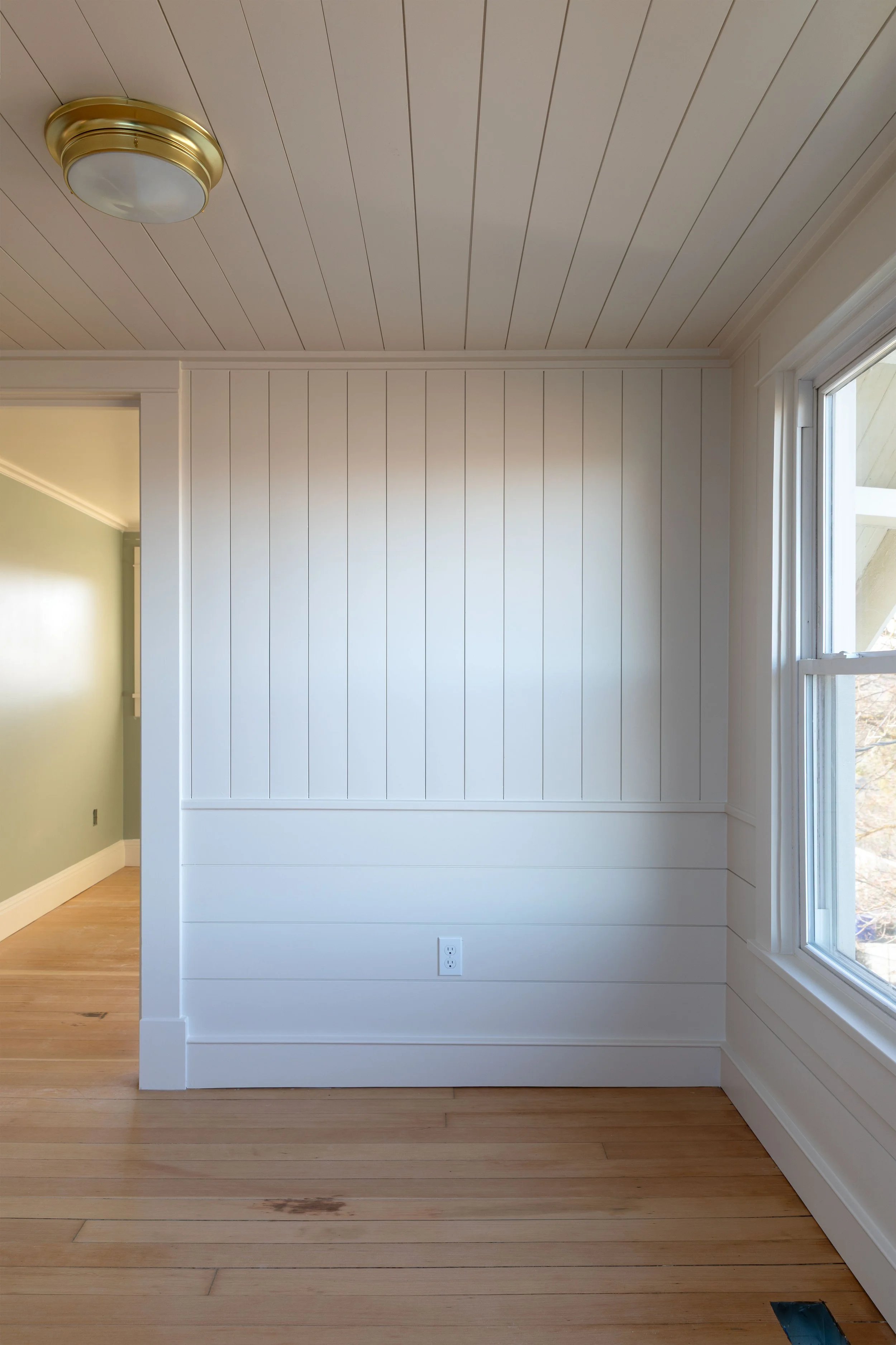 Nickel gap wall paneling in upstairs snug with vertical and horizontal boards in old home renovation